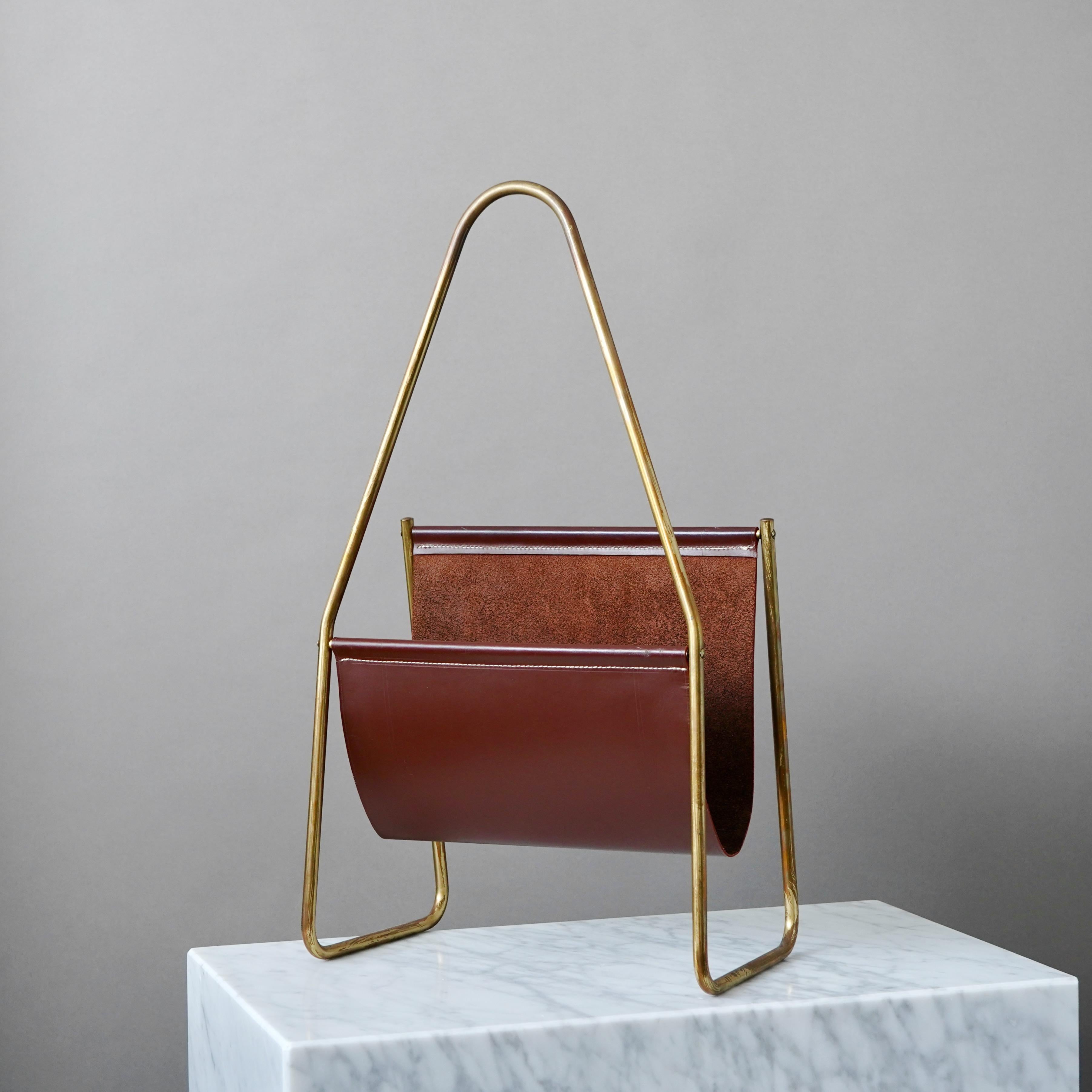 Un bellissimo portariviste/edicola di metà secolo in ottone e pelle marrone, con un'incredibile patina originale. 

Progettato e prodotto da Carl Auböck, in Austria, negli anni '50 o '60.
Model No. 3808. Venduto presso Illum Bolighus a Copenaghen,