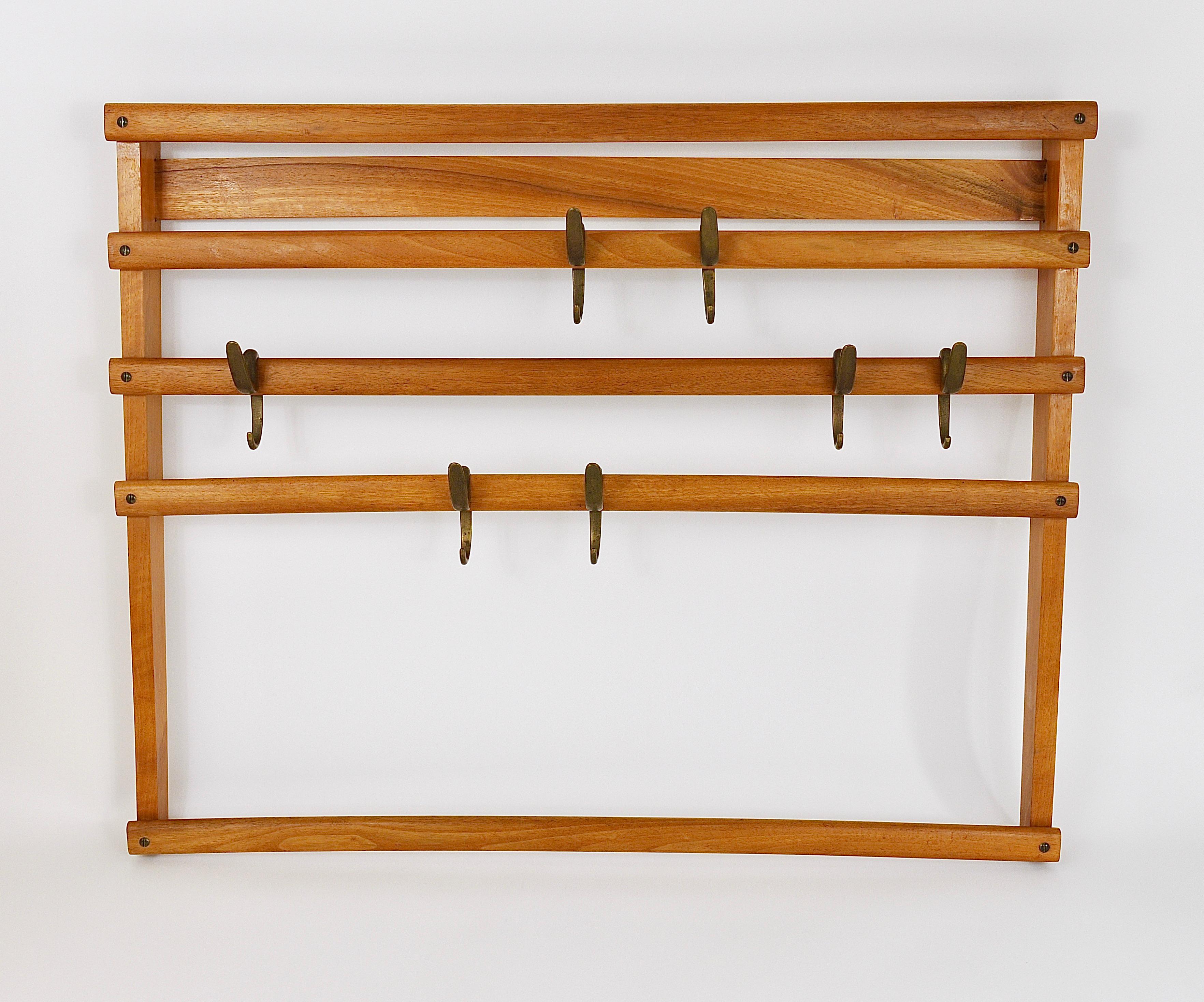 An elegant modernist wall-mounted coat rack from the 1950s. An original and old vintage object, designed and executed by the Austrian architect and designer Carl Auböck. The frame is made of beechwood and is equipped with seven lovely patinated