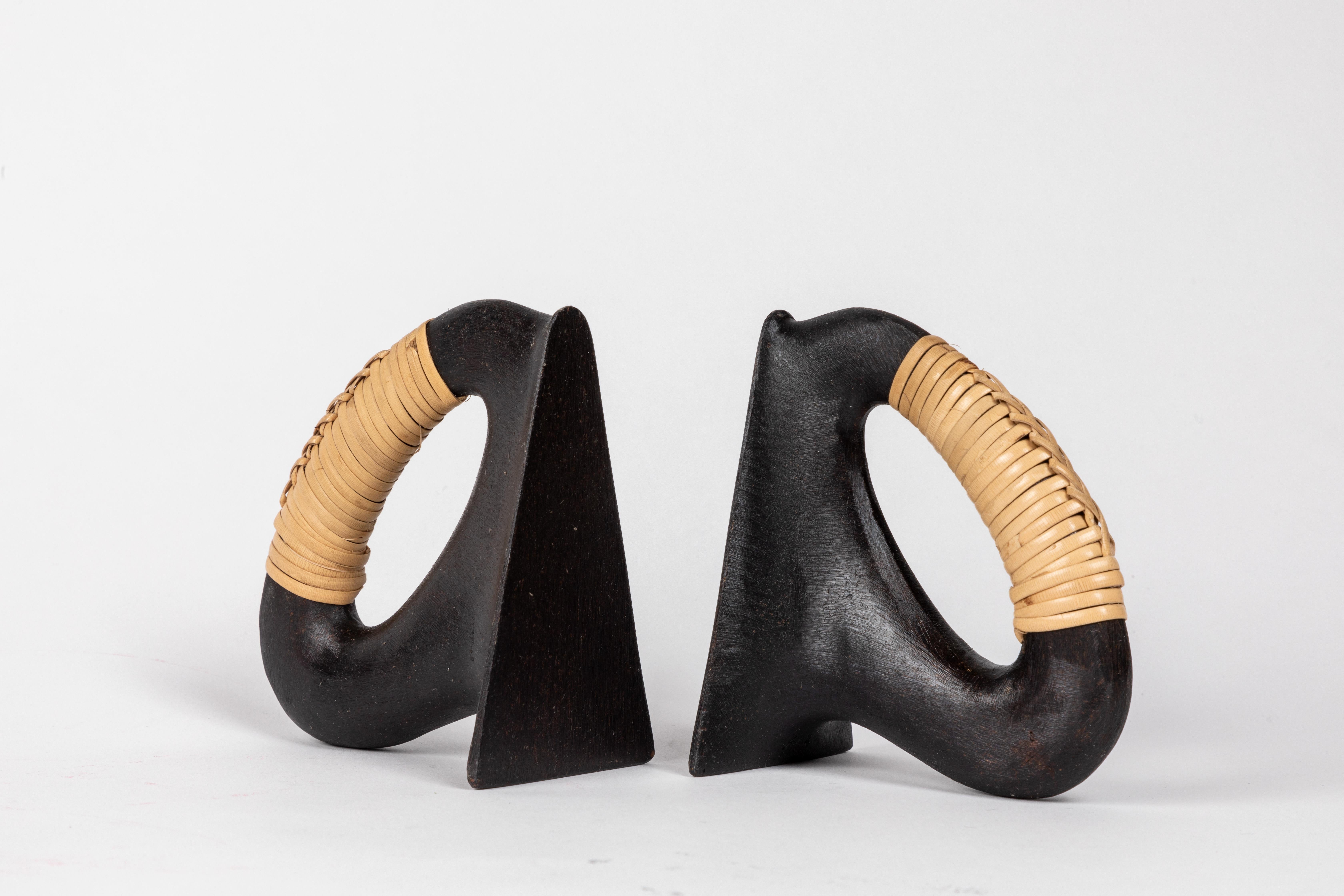 Pair of Carl Auböck model #3530 'Flatiron' patinated brass and cane bookends. Designed in the 1950s, this incredibly refined and sculptural pair of bookends are executed in patinated brass and handwoven cane. 

Price is for the pair. One pair in