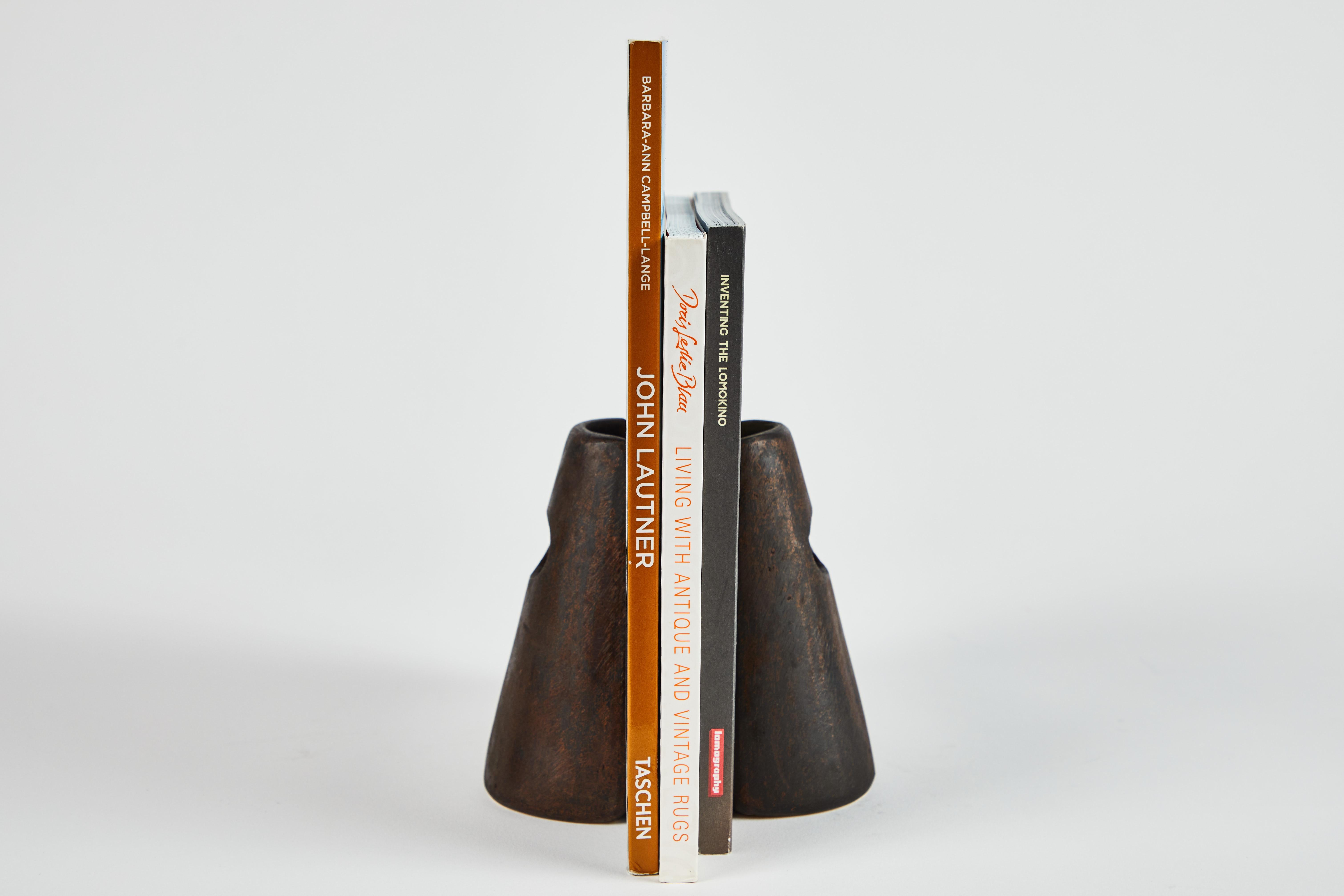 Ein Paar Carl Auböck Modell #4842 patinierte Messing Buchstützen. Dieses unglaublich raffinierte und skulpturale Paar Buchstützen wurde in den 1950er Jahren entworfen und ist aus patiniertem Messing gefertigt. 

Der Preis gilt für das Paar. Zwei