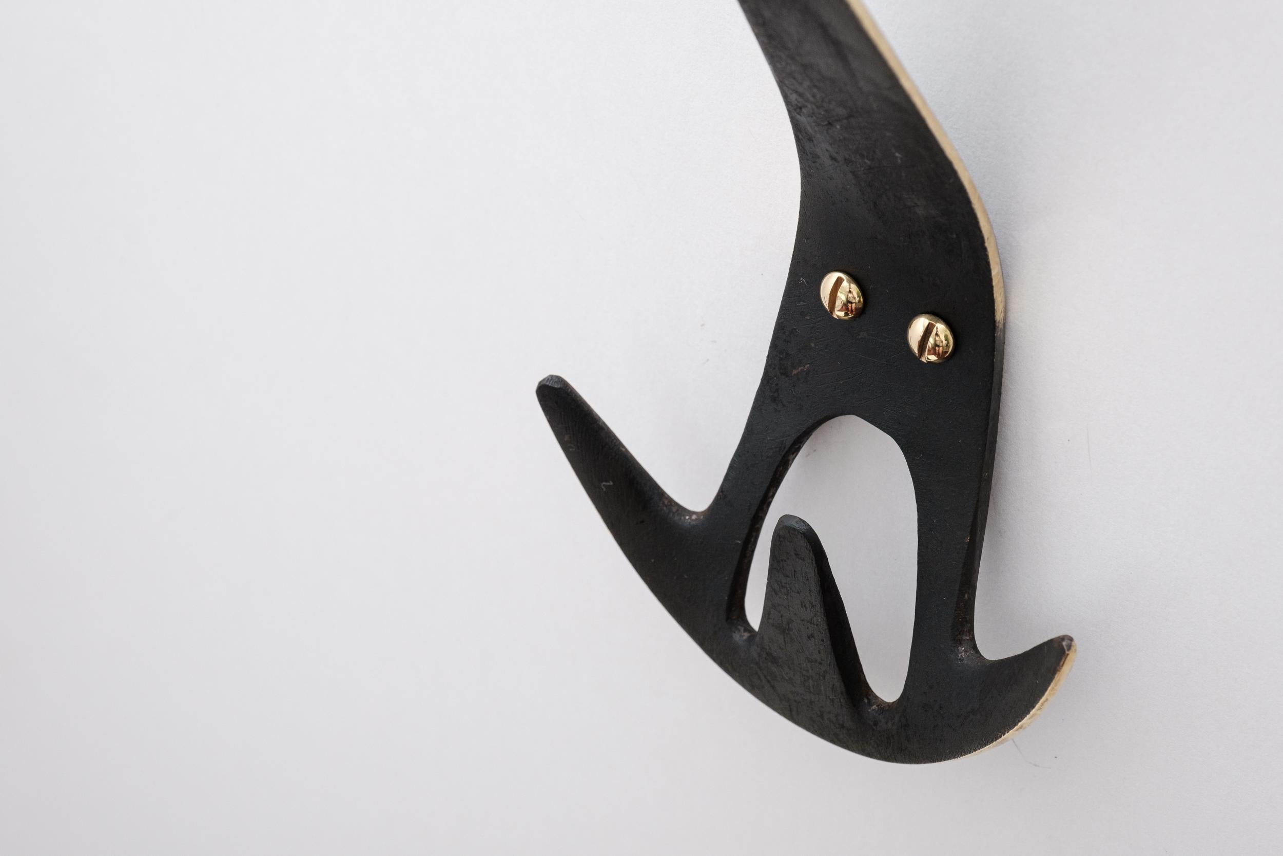 Carl Auböck Model #4903 patinated brass hook. Designed in the 1950s, this versatile and Minimalist Viennese hook is executed in patinated brass by Werkstätte Carl Auböck, Austria. 

Produced by Carl Auböck IV in the original Auböck workshop in the