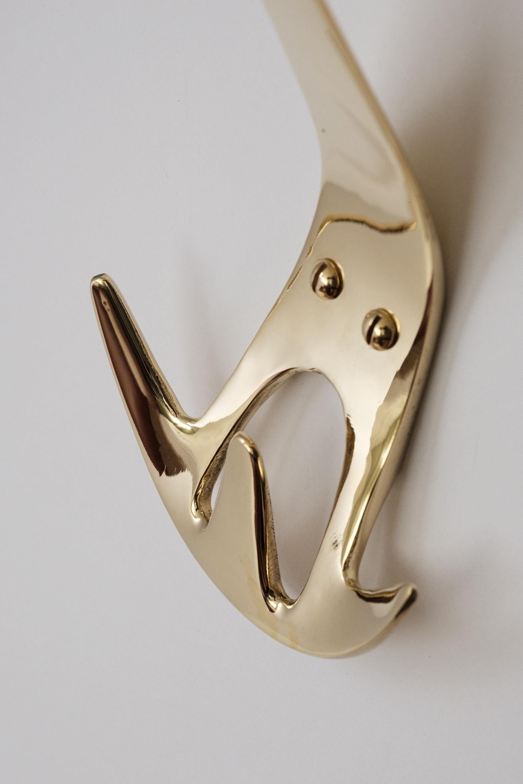 Carl Auböck Model #4903 polished brass hook. Designed in the 1950s, this versatile and Minimalist Viennese hook is executed in polished brass by Werkstätte Carl Auböck, Austria. 

Produced by Carl Auböck IV in the original Auböck workshop in the 7th