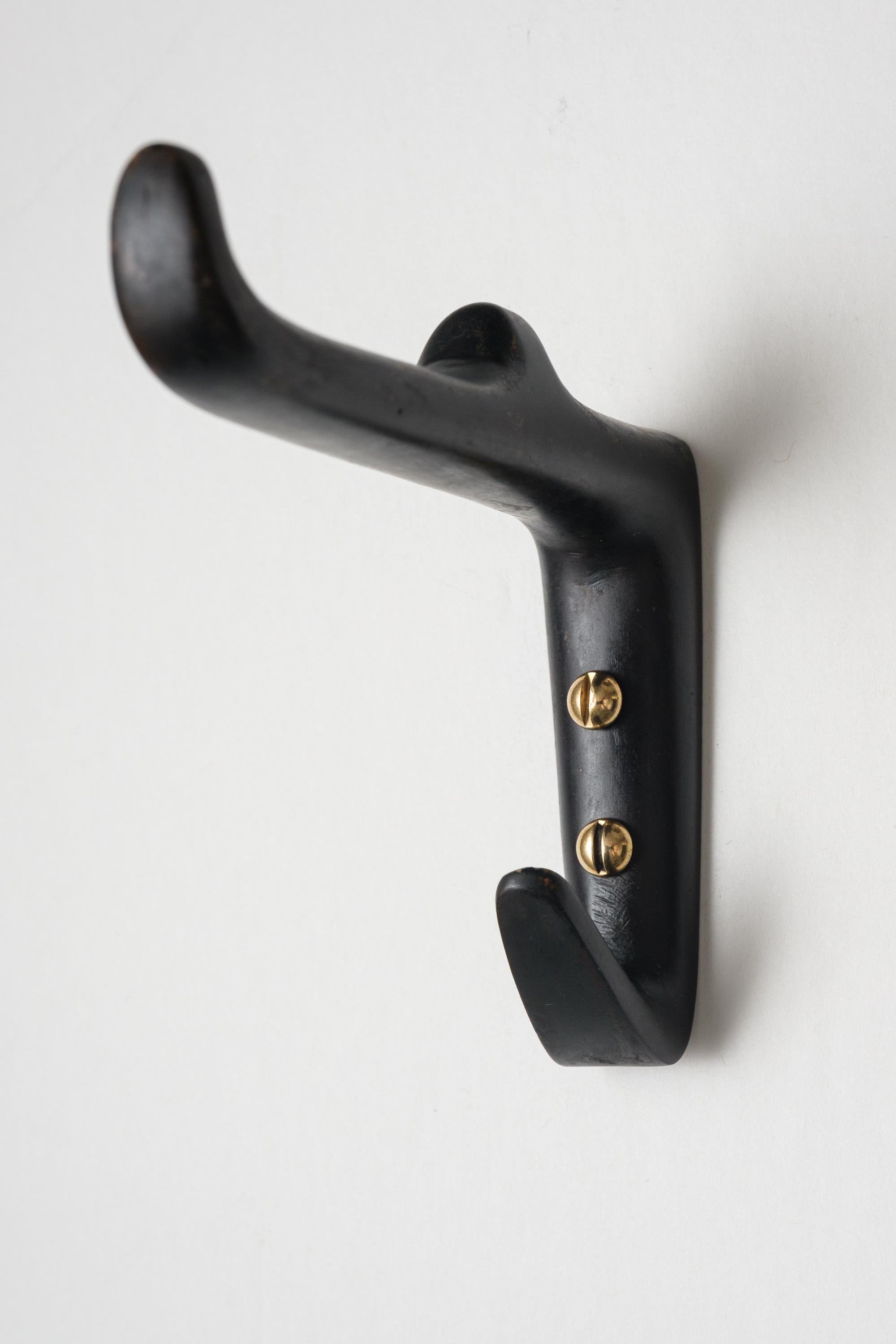 Carl Auböck #4965 patinated brass hook. Designed in the 1950s, this versatile and Minimalist Viennese hook is executed in darkly patinated and polished brass by Werkstätte Carl Auböck, Austria.

Produced by Carl Auböck IV in the original Auböck