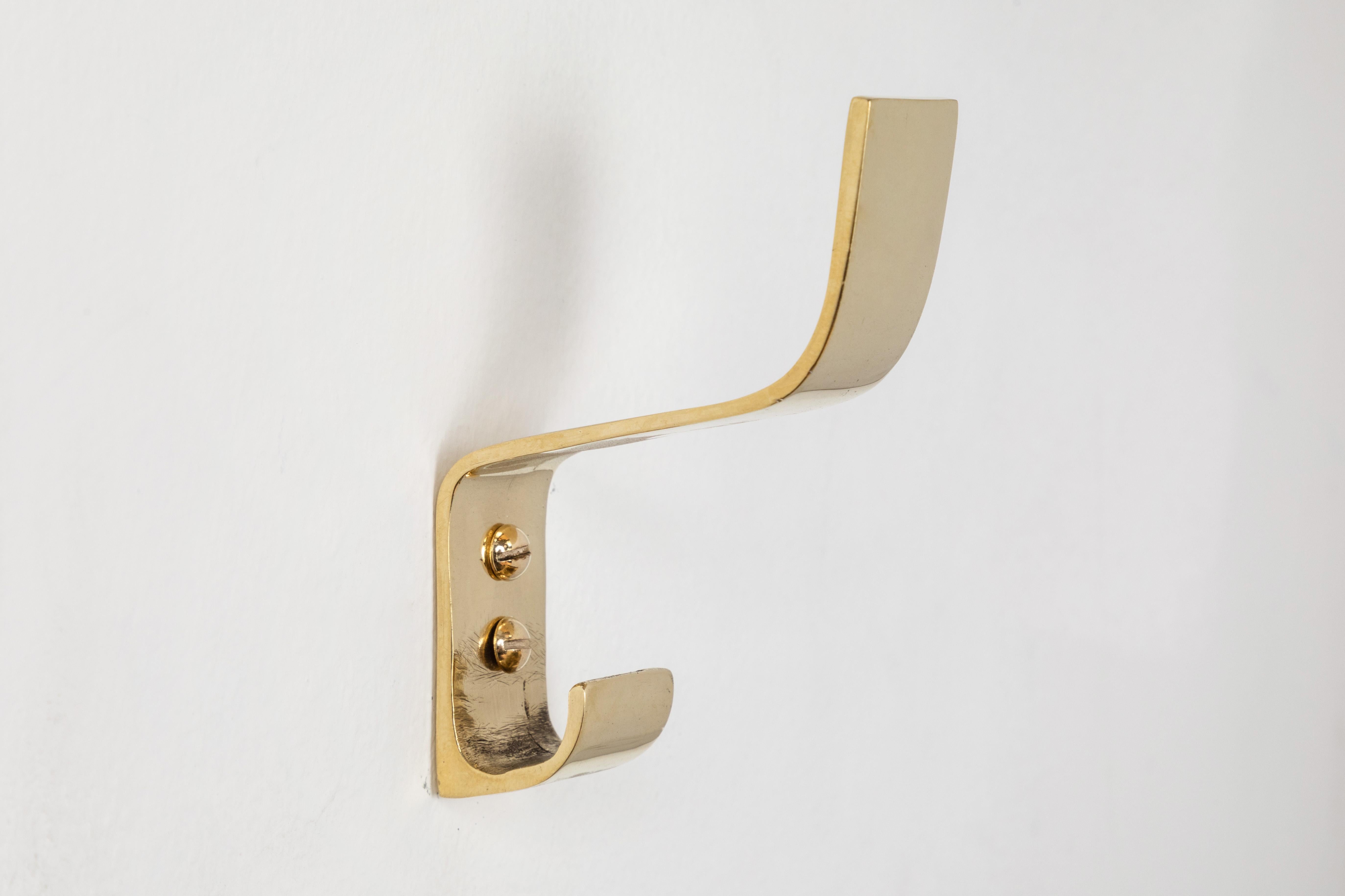 Carl Auböck model #5261 brass hook. Designed in the 1950s, this versatile and Minimalist Viennese hook is executed in polished brass by Werkstätte Carl Auböck, Austria. 

Produced by Carl Auböck IV in the original Auböck workshop in the 7th district