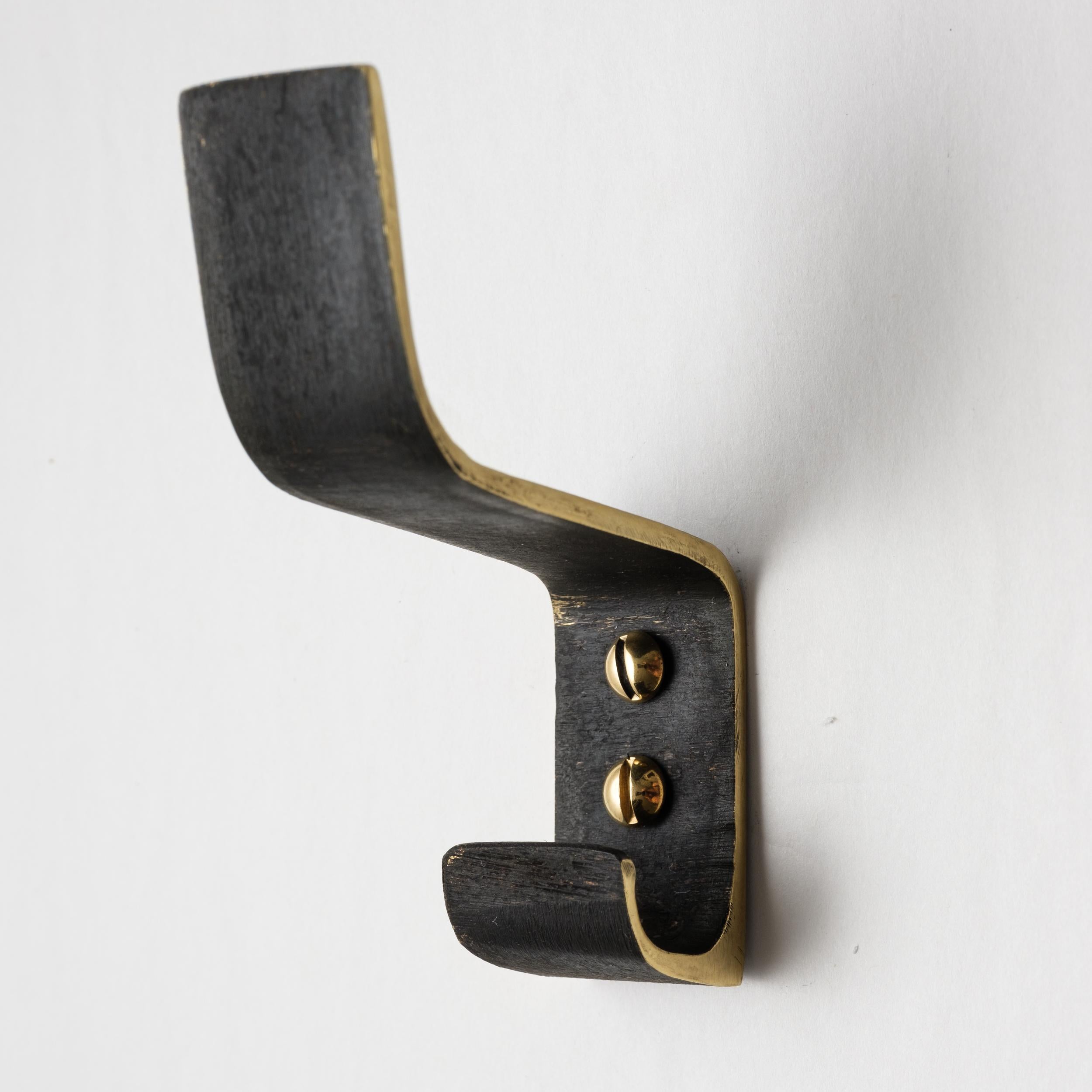 Carl Auböck model #5261 patinated brass hook. Designed in the 1950s, this versatile and Minimalist Viennese hook is executed in patinated and polished brass by Werkstätte Carl Auböck, Austria. 

Produced by Carl Auböck IV in the original Auböck