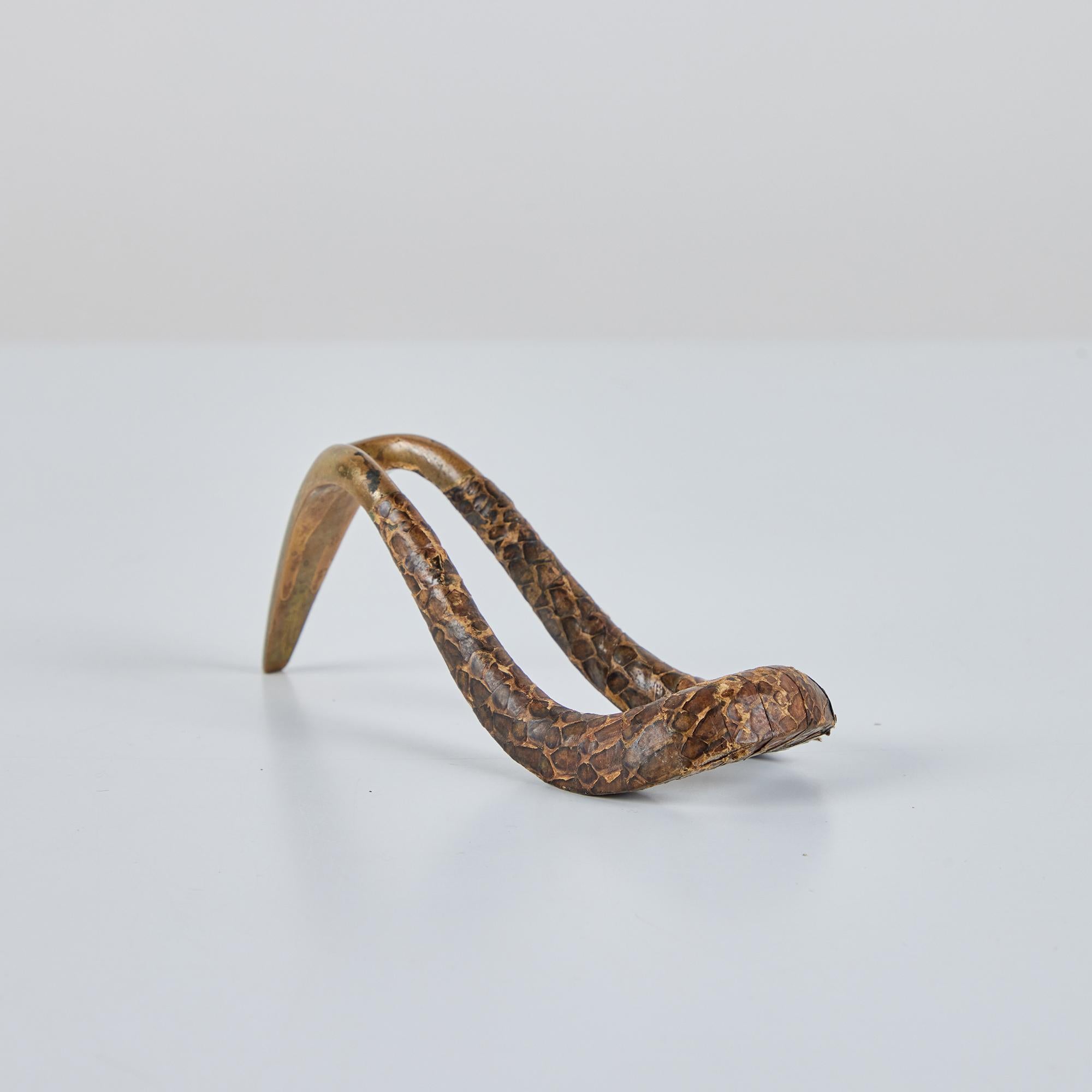 Porte-pipe en laiton et peau de serpent du designer industriel autrichien Carl Auböck, c.1950. Le cadre incurvé en laiton est partiellement enveloppé d'une peau de serpent marron et tan.

Dimensions :
5