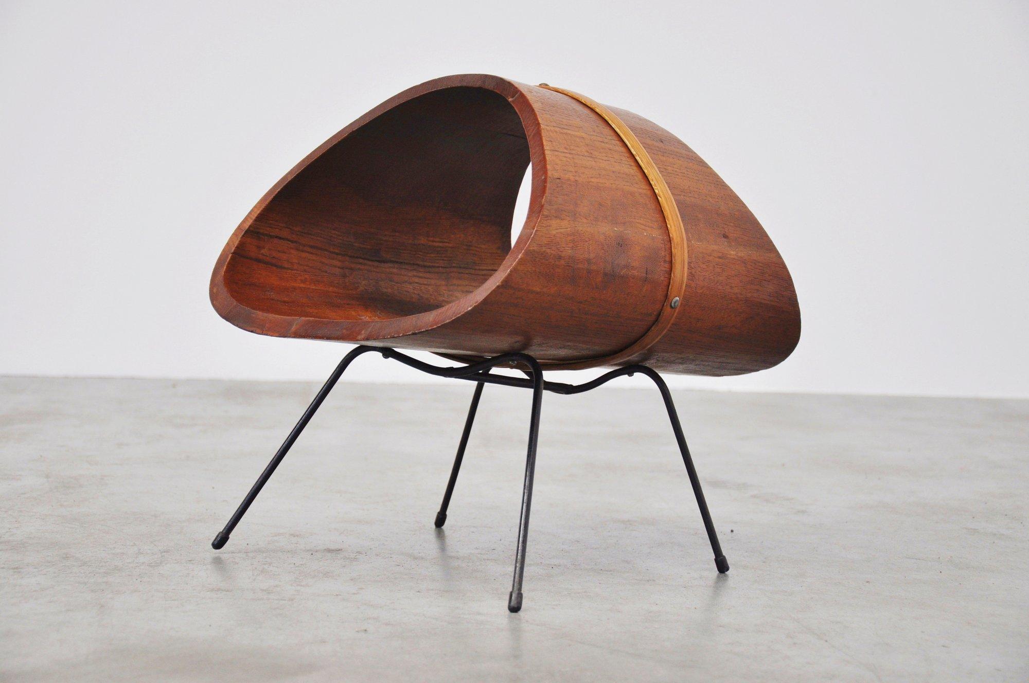 Fantastic dynamic shaped magazine stand, Vienna 1956. This cool magazine stand was made of a massive wooden parts and was finished with a wooden slat and brass nails. The frame is black lacquered metal. This magazine rack is more like some kind of a
