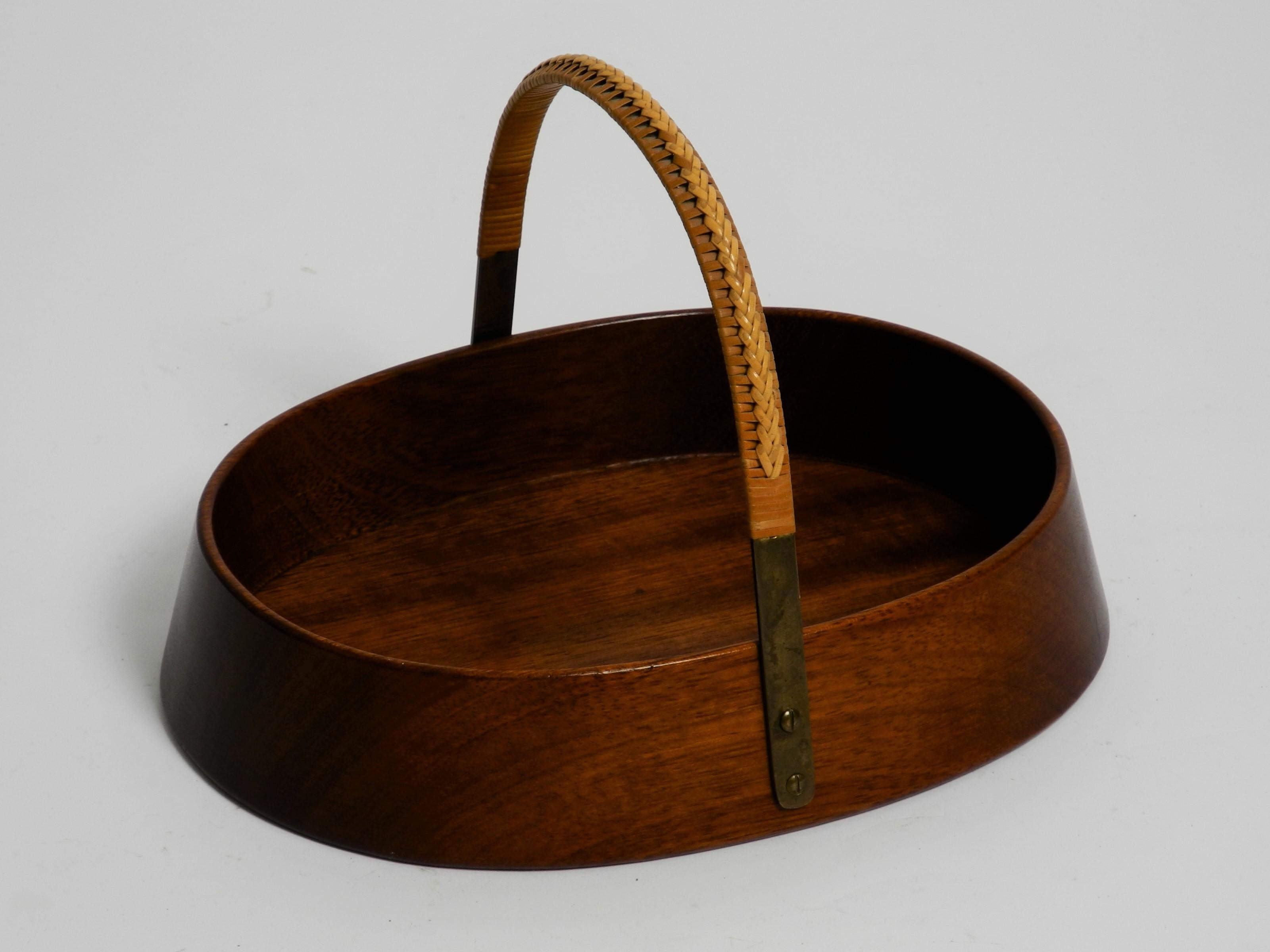 Original 1950s bowl element made by of solid teak wood and brass loop with rattan at the top for carrying. This fantastic piece was designed by Carl Auböck in the 1950s, and handcrafted in his Workshop in Vienna, Autria in the 1950s. 

It is a