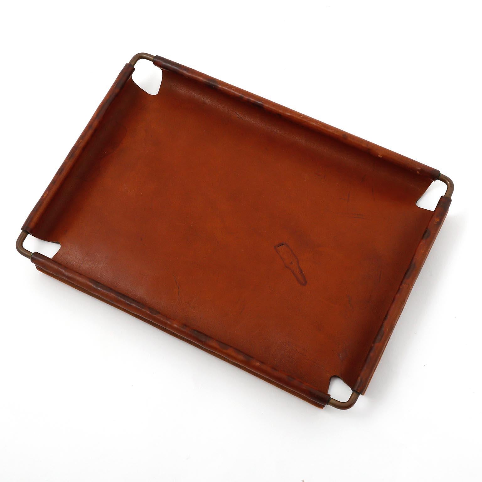 A leather and brass tray designed by Carl Auböck, manufactured by Carl Auböck workshop in midcentury, circa 1950.
The aged brass and leather show signs of wear and use. An authentic handmade piece with nice patina on brass and leather.
This tray