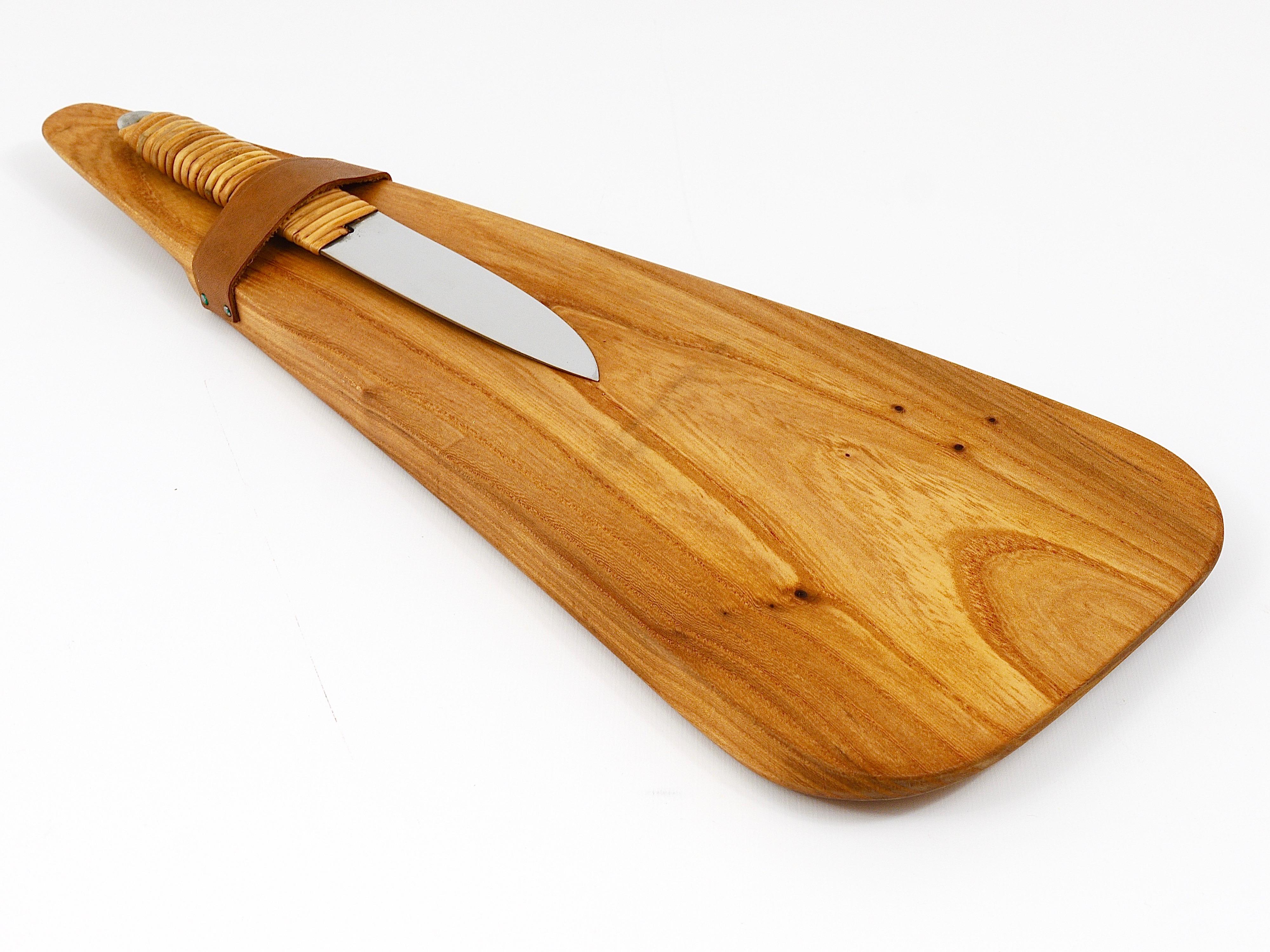 A beautiful triangular cutting board and knife set, designed and crafted in the 1950s by Carl Auböck. The cutting board is made of walnut and features leather accents, showcasing Auböck's renowned craftsmanship. The knife, manufactured by Amboss