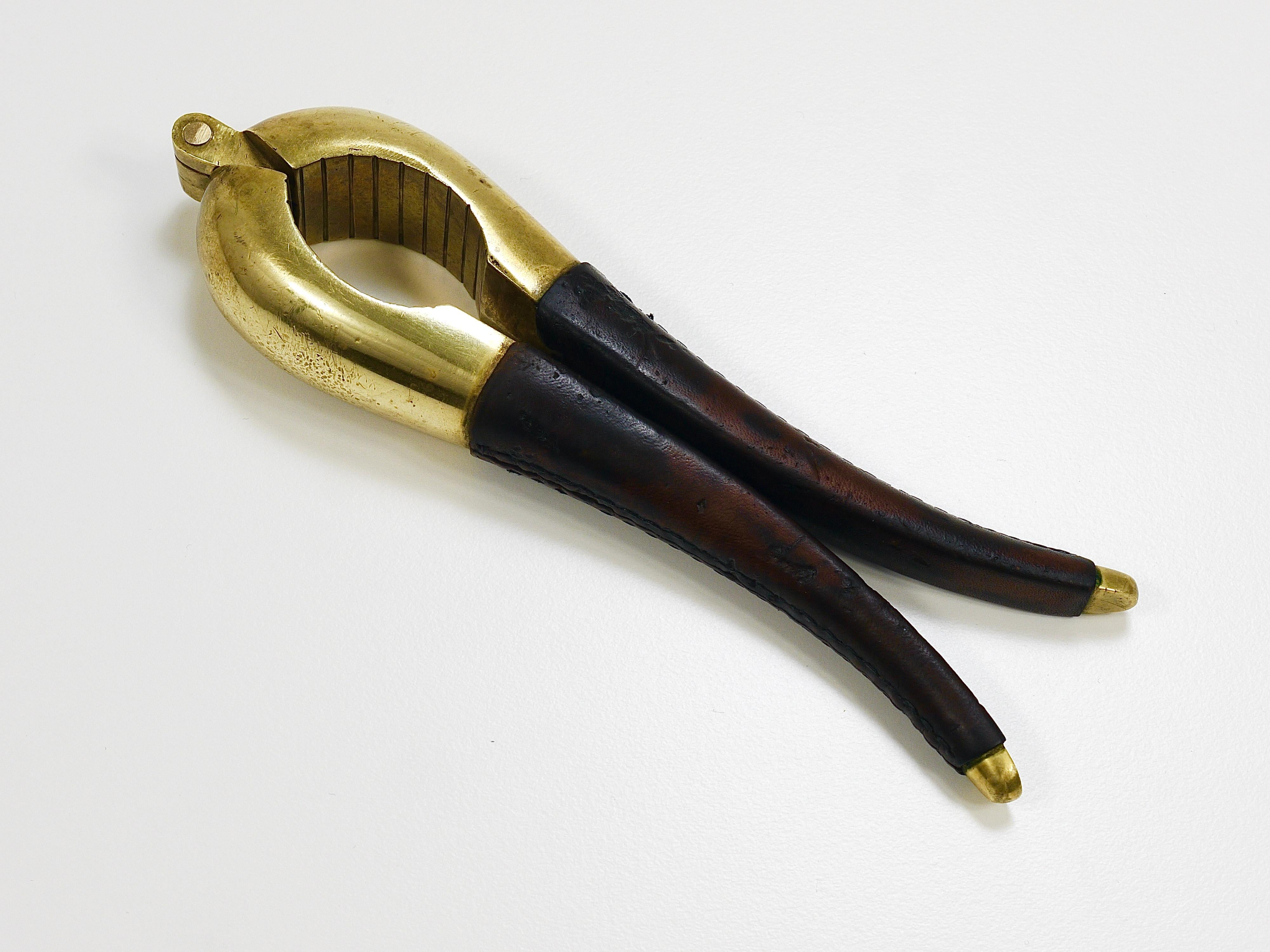Un bellissimo schiaccianoci in ottone, modello No. 4051-4, progettato e prodotto negli anni '50 da Werkstätte Carl Auböck a Vienna, in Austria. Questo pesante pezzo in ottone massiccio è dotato di manici avvolti in pelle marrone scuro. Essendo un