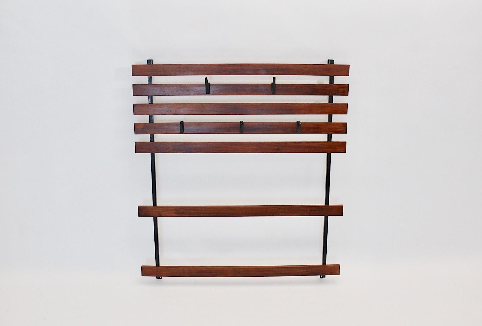 A rare and early vintage wall mounted coat rack, which was designed and manufactured Vienna, circa 1948.
The coat rack was made of black lacquered metal frame and 7 brown stained oak wooden slats.
Five blackened cast aluminum hooks, which are