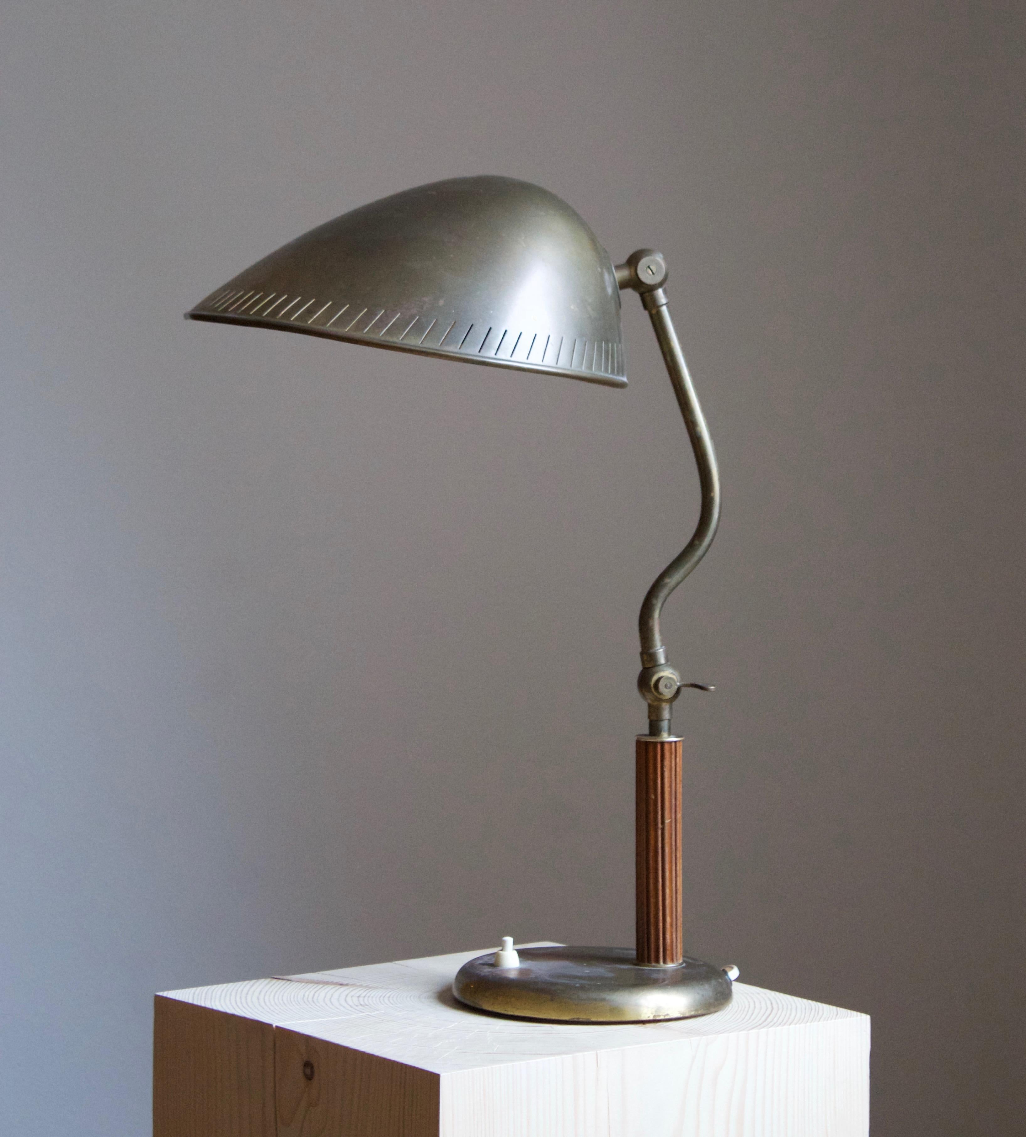 A functionalist adjustable table lamp / desk light. Design attributed to Carl-Axel Acking. Likely produced by Böhlmarks. Features a base and an organic shade in brass, rod in carved and stained elm.

 