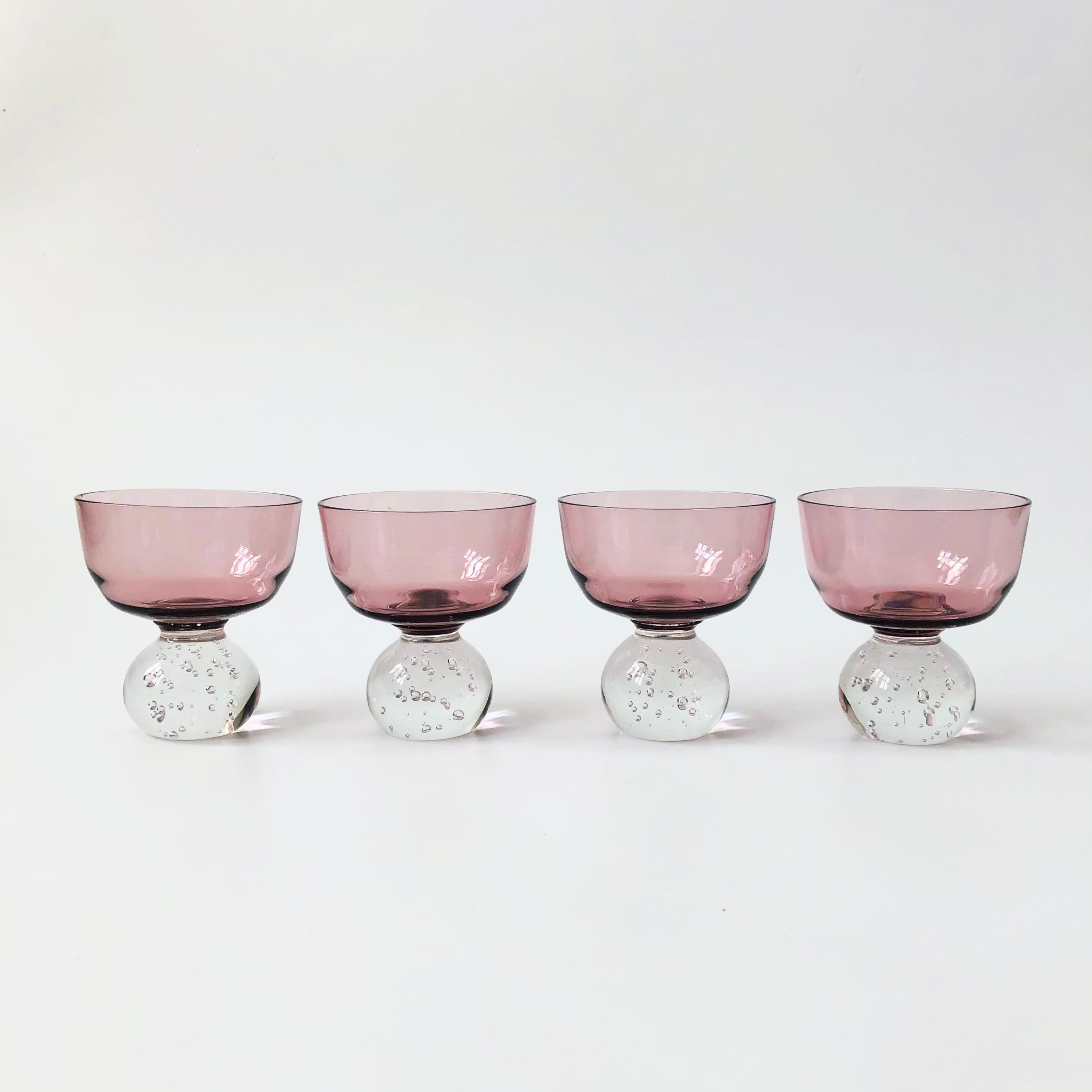 A set of 4 art glass coupes by mid century glass maker, Carl Erickson. Each has a lovely pale purple top with a blown glass base formed into a sphere shape with controlled bubbles throughout.


