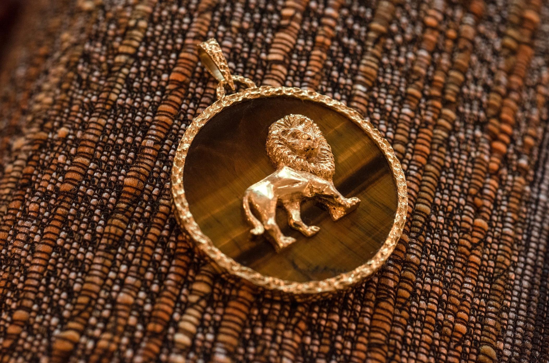 An original tiger's eye and 18 karat gold Leo zodiac astrology pendant  of medium size, by Carl Bucherer,  c. 1970. Stamped ' CB', 750.  

At the center of this Carl Bucherer pendant is a tiger eye gemstone, known for its distinct golden-brown color