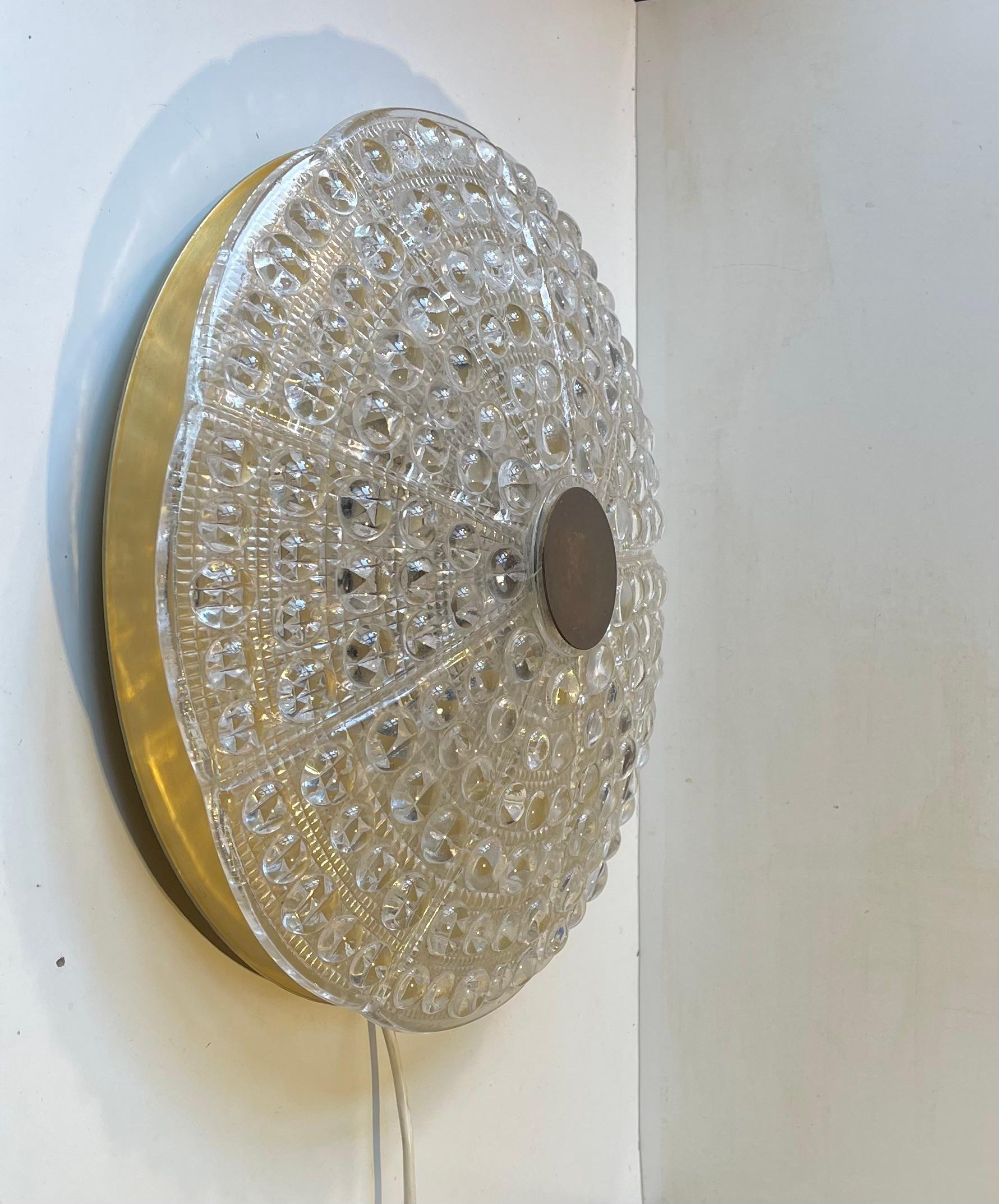 Crystal and brass flush mount or large wall sconce designed by Carl Fagerlund and manufactured by Orrefors in Sweden during the early 1960s. Original configuration with 6 sockets for 6 40 watt bulbs. Measurements: D: 39 cm, H/D: 15 cm. Working