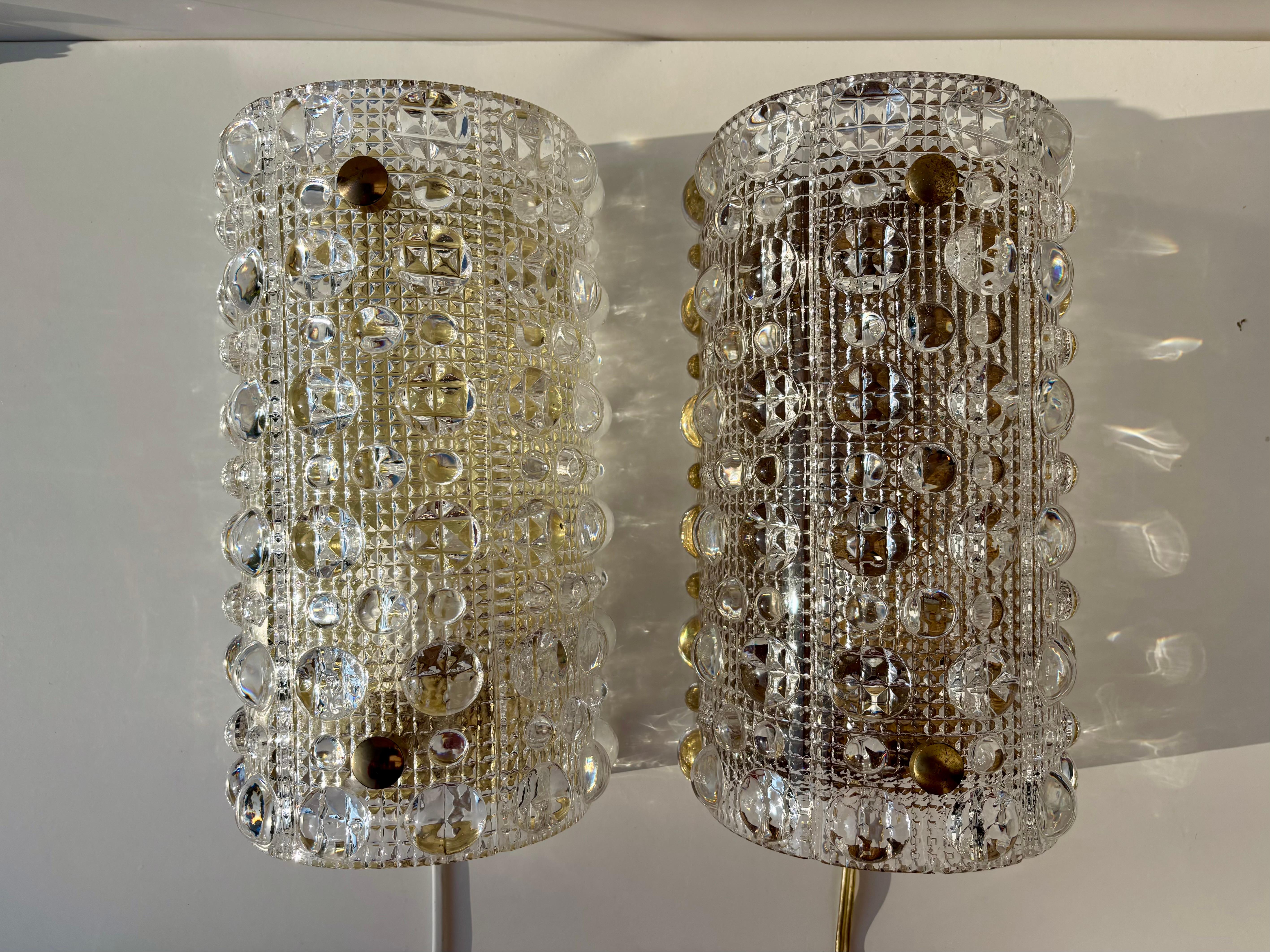 1 of 2 stunning bubble textured crystal wall sconces by Swedish designer Carl Fagerlund for Orrefors Glasbruk. Manufactured in the small town of Orrefors in Sweden in the 1950s. Beautifully curved glass plate on brass mount with brass hardware. No