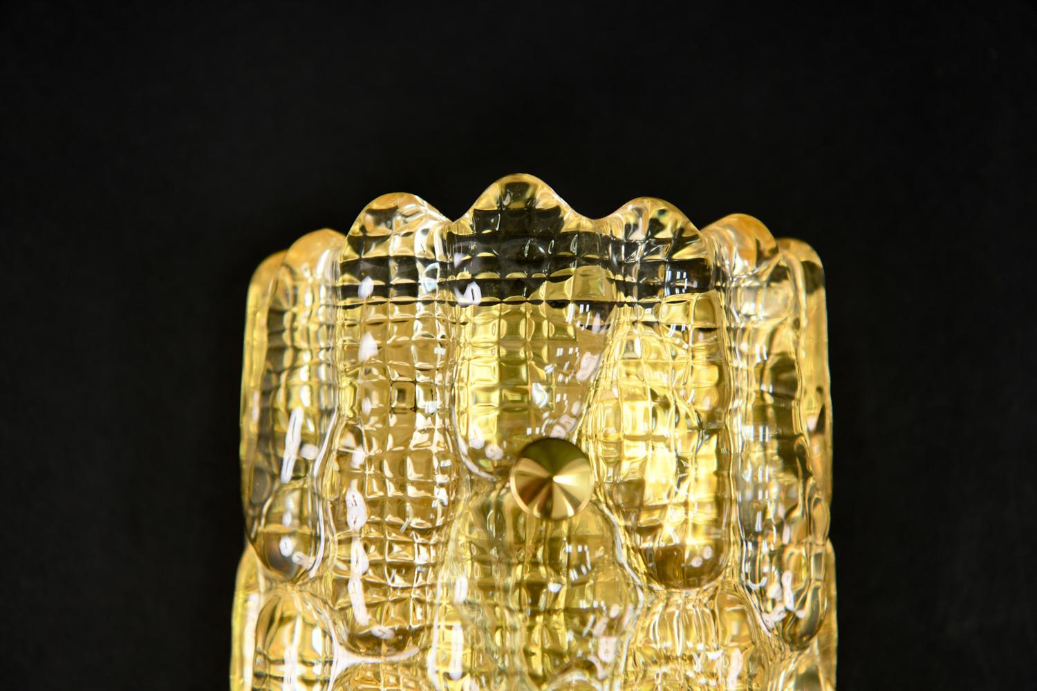 A Swedish midcentury sconce designed by Carl Fagerlund for Orrefors. Featuring a textured crystal body with a brass backplate and details. Multiple available.
