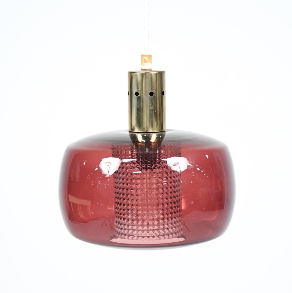 A Swedish mid-century pendant light designed by Carl Fagerlund for Orrefors, c. 1960's, featuring cranberry glass shade encasing inner textured crystal shade.