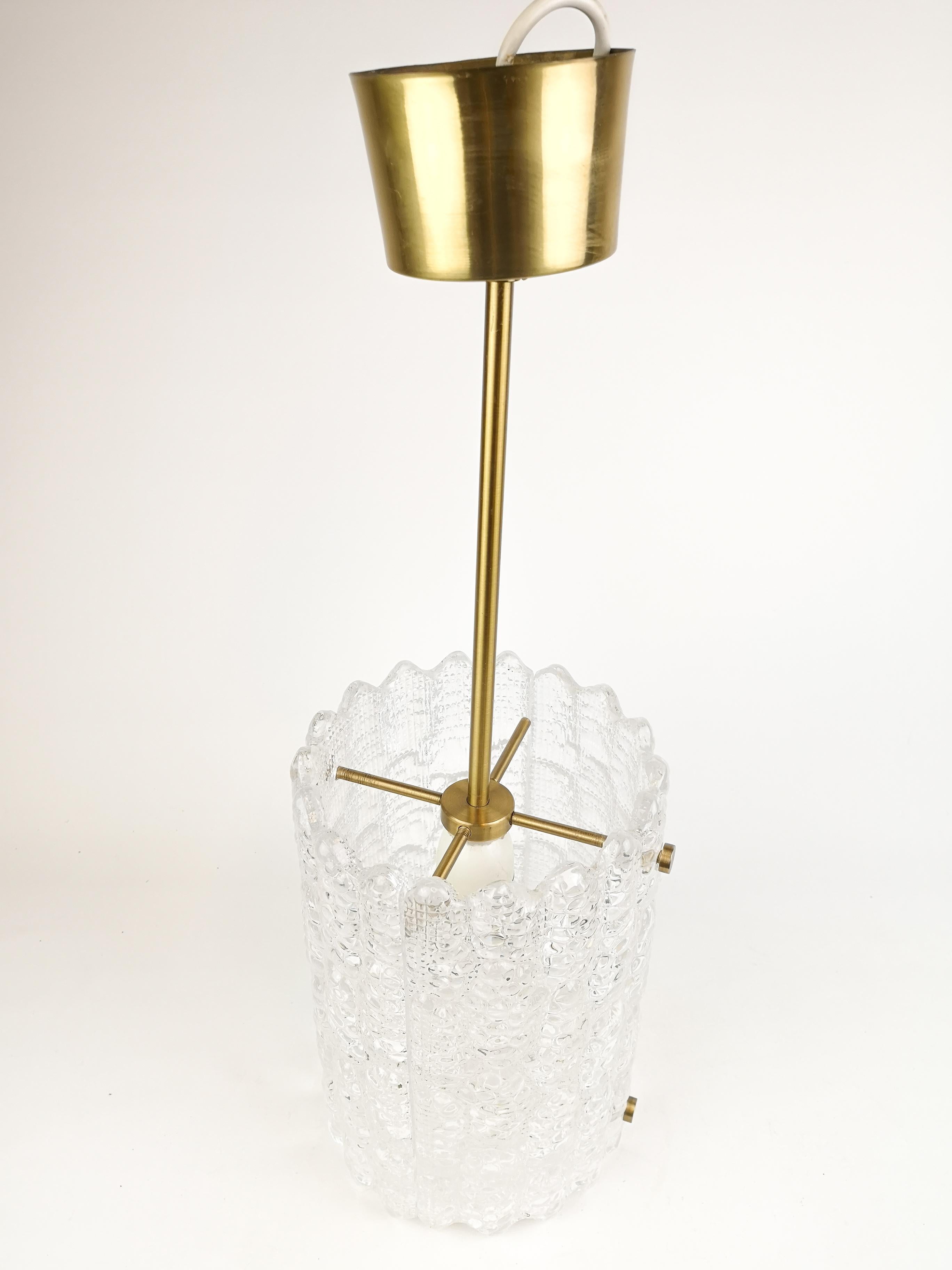 This stunning Mid-Century Swedish modern cylinder pendant was designed by Carl Fagerlund for Orrefors Glasbruk in the 1960s.Clear textured crystal with scalloped edges and great handcrafted brass parts. Wonderful light when the crystal light hits