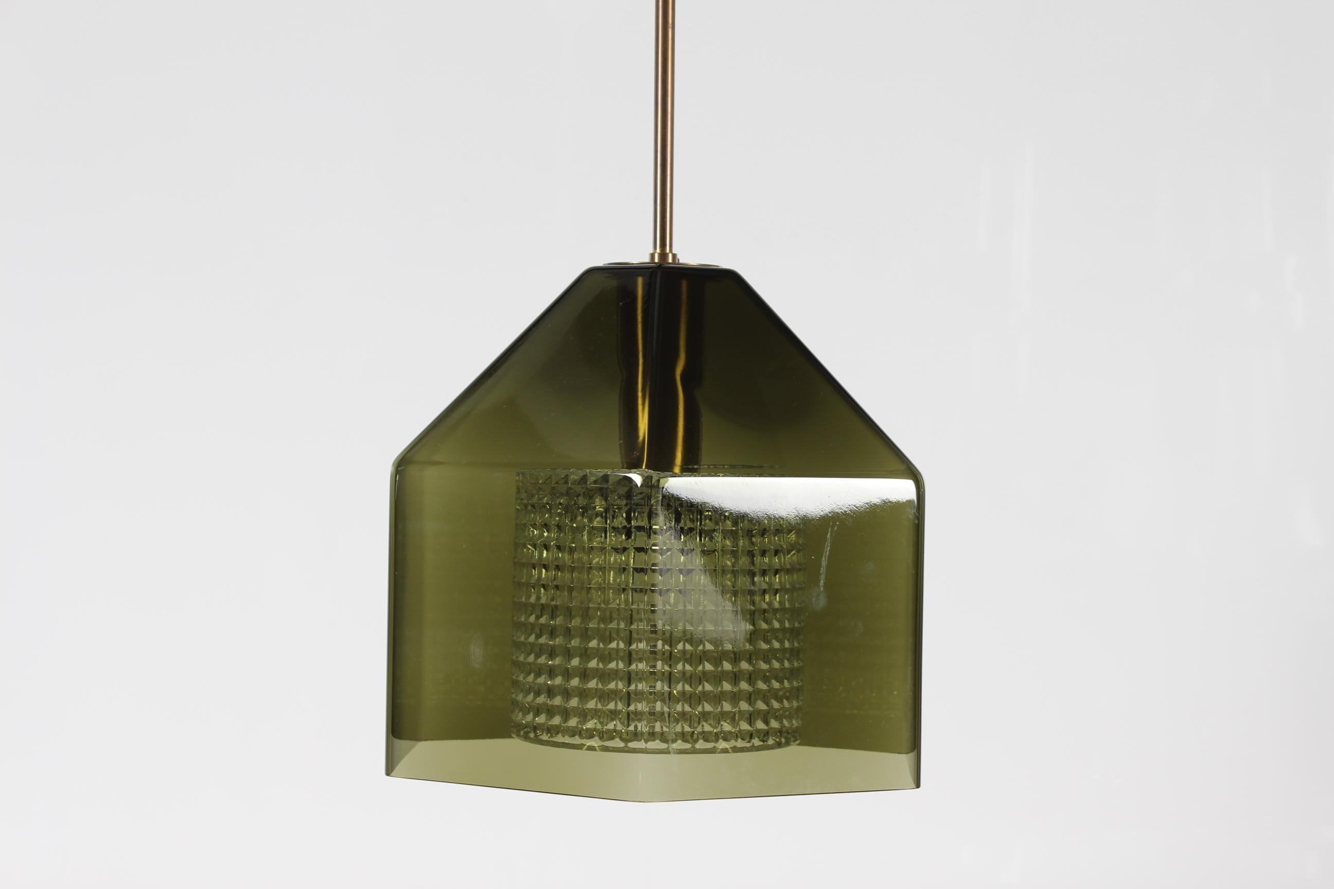 Colgante de cristal vintage del diseñador sueco Carl Fagerlund para Orrefors. Fabricado en la década de 1960. 

La lámpara está hecha con un núcleo de cristal translúcido prensado cubierto por una pantalla hexagonal de cristal verde oscuro. Equipado
