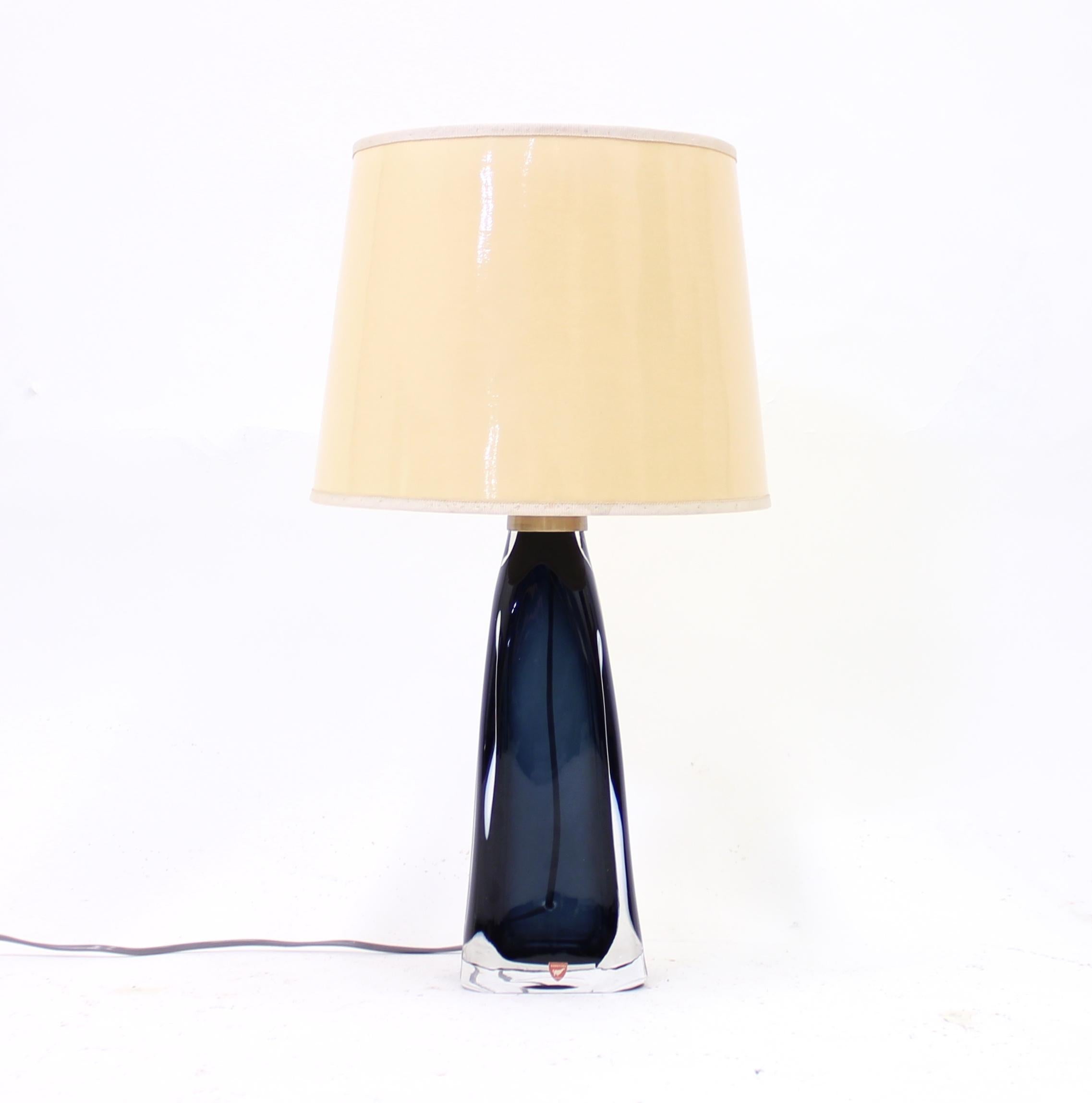Blue glass table lamp designed by Carl Fagerlund for Swedish glass manufacturer Orrefors in the 1960s. Top of the base with brass fitting and bright yellow lacquered shade. Marked with Orrefors sticker on the front and also inscribed by Orrefors