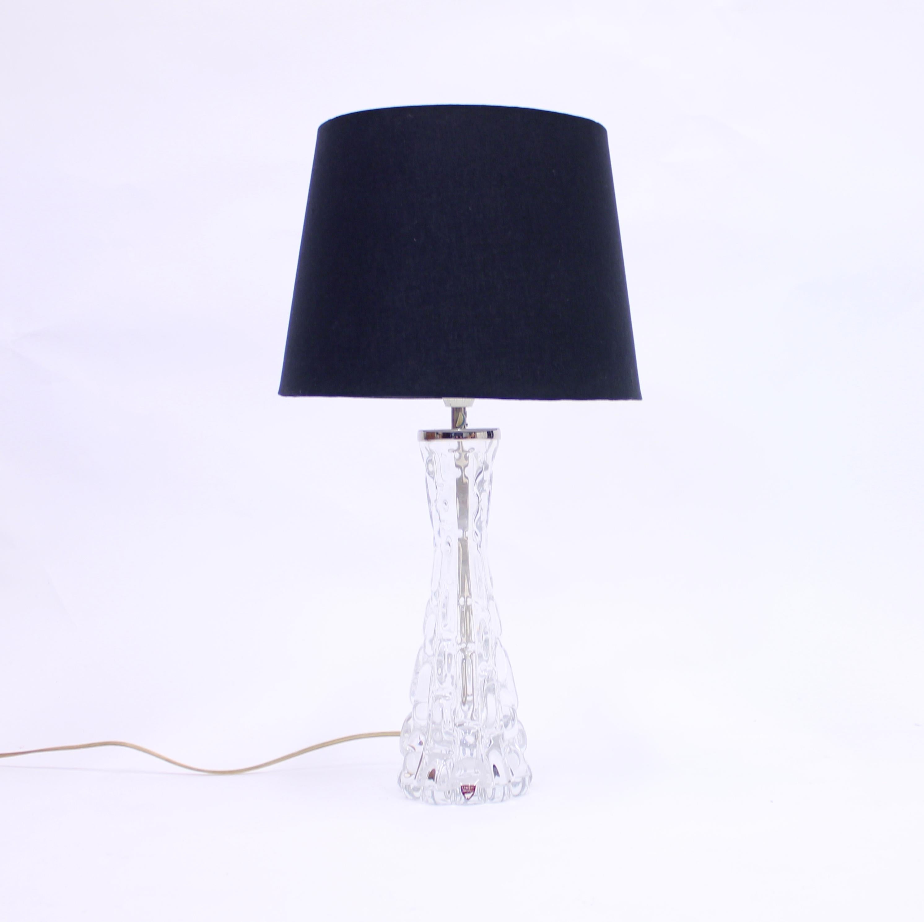 Glass table lamp designed by Carl Fagerlund for Swedish glass manufacturer Orrefors in the 1960s. Top of the base with chrome fitting and a new black fabric shade. Labeled by Orrefors both on the chrome part and also on the front with stickers. Good