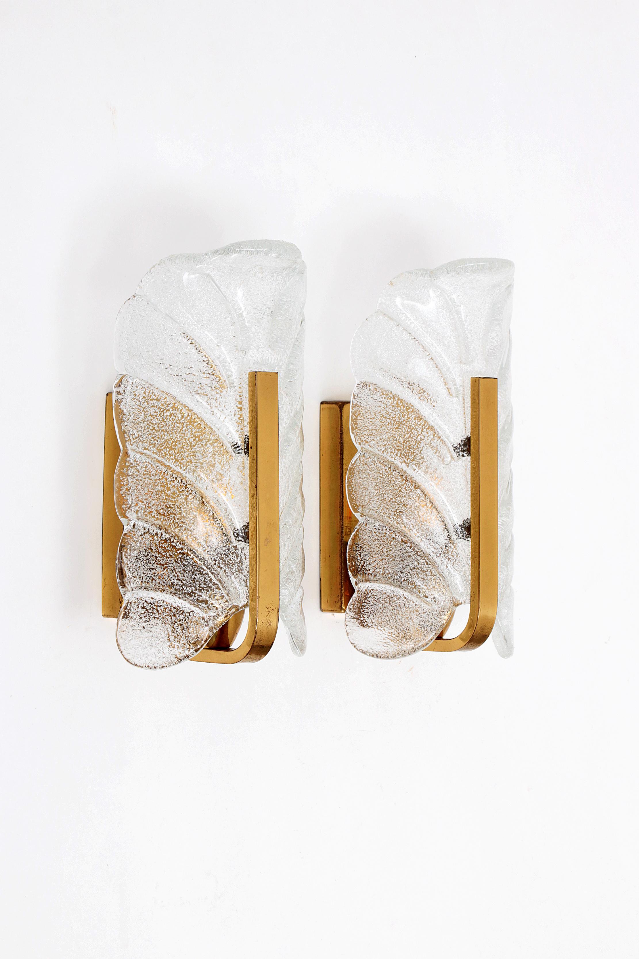 Pair of Scandinavian glass wall lamps/candlesticks by Carl Fagerlund for Orrefors (1960s). Clear glass shade representing a leaf (matte embossed on the inside and glossy on the outside) on polished brass. Spreads the light beautifully (see