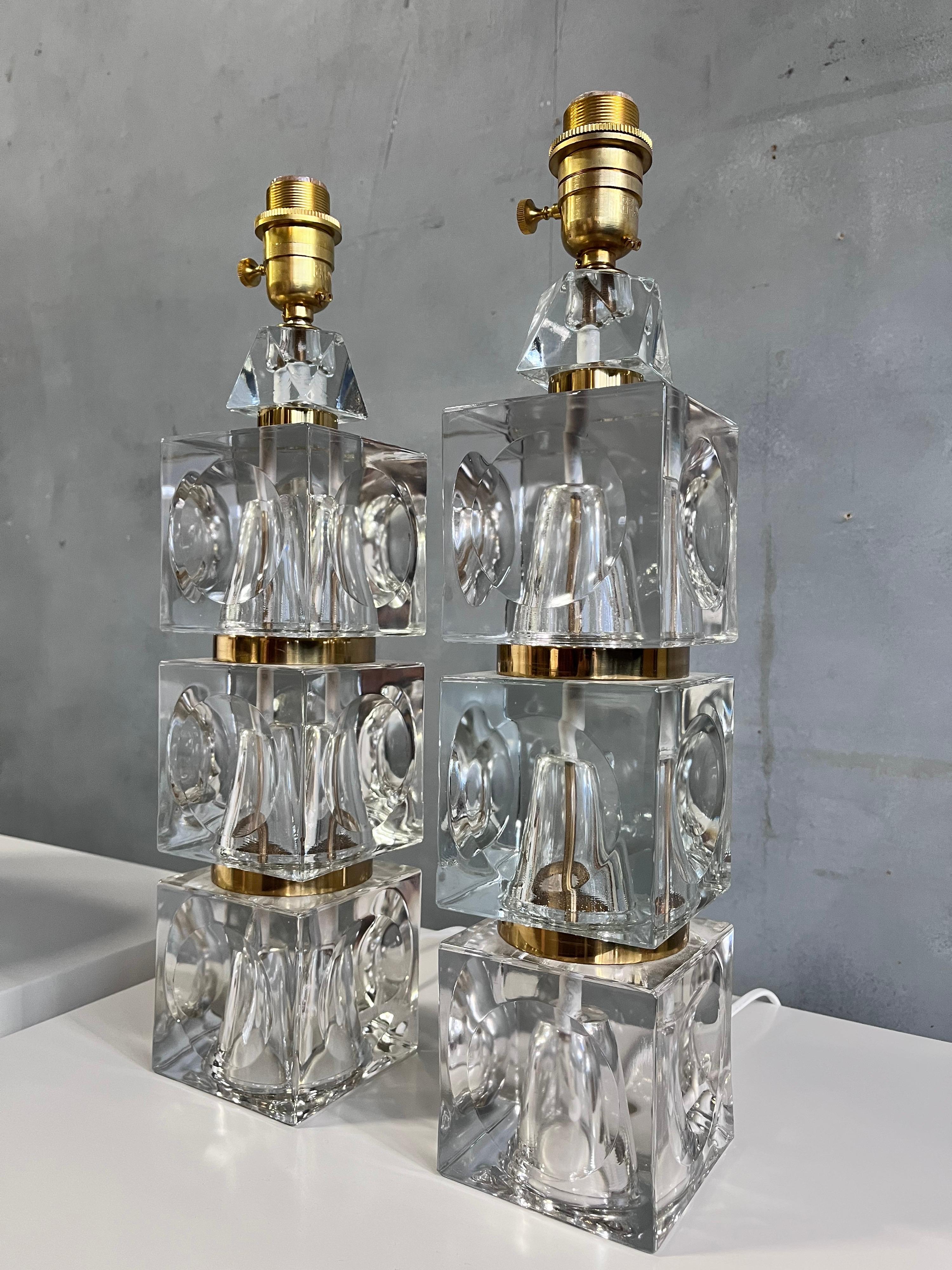 Gorgeous pair of table lamps with stacked glass crystal and brass accents. No scratches or dings to the glass in near flawless condition. Each crystal cube has a concave inset pattern reflecting and amplifying the light around the base. A wonderful
