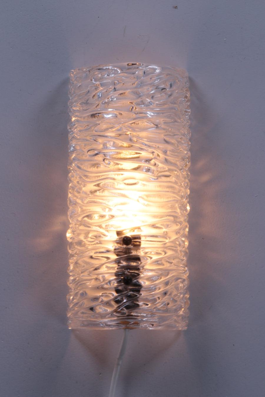 Carl Fagerlund Wall Lamp Model 8493 Made by Orrefors, 1960

Designed by Carl Fagerlund for Orrefors Sweden.

The lamp is made of thick pressed glass with ice relief, an iron fixture and metal knobs.

The light is beautifully spread through the