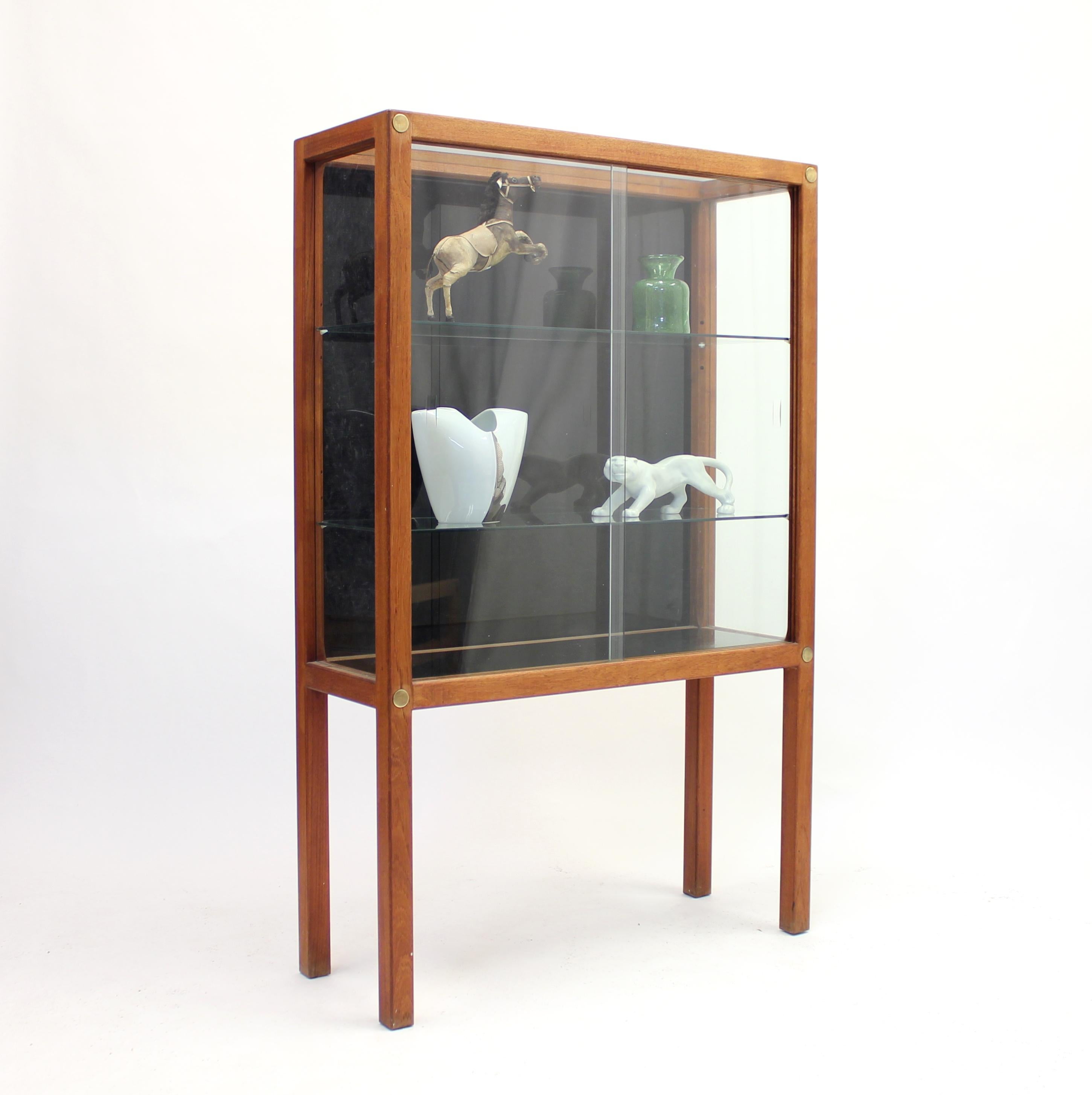 Rare vitrine display cabinet in teak with brass details designed by Carl Gustaf Hiort af Ornäs in the 1950s. Produced by his long time collaborator Huonekalu Mikko Nupponen Oy in the town of Lahti, Finland. This cabinet was produced in a few