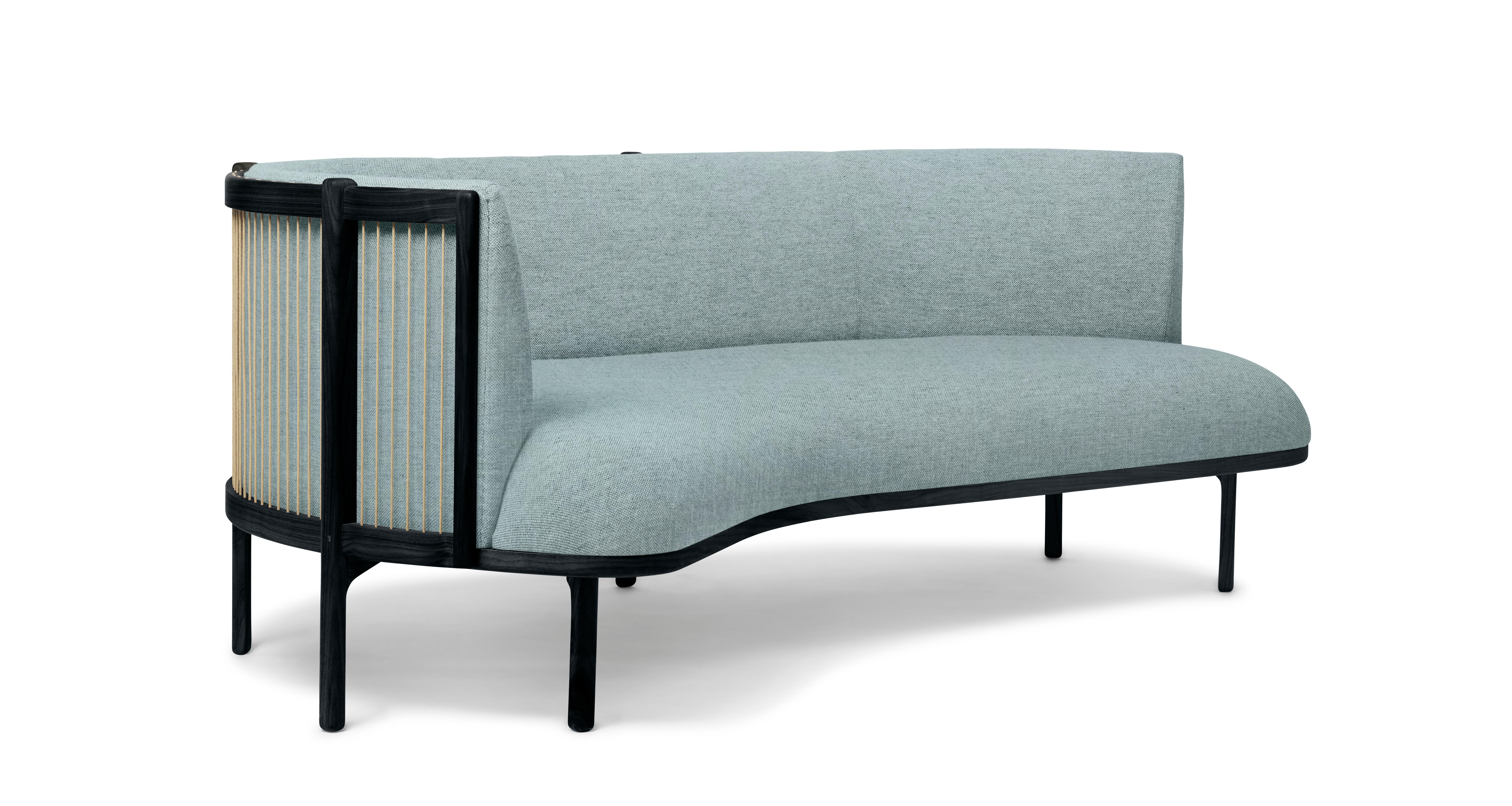 The Sideways sofa from Rikke Frost combines classic materials – wood, paper cord, and high-quality upholstery textile – with a modern asymmetric shape. The steam-bent backrest is shaped from solid wood and woven paper cord for a light, elegant