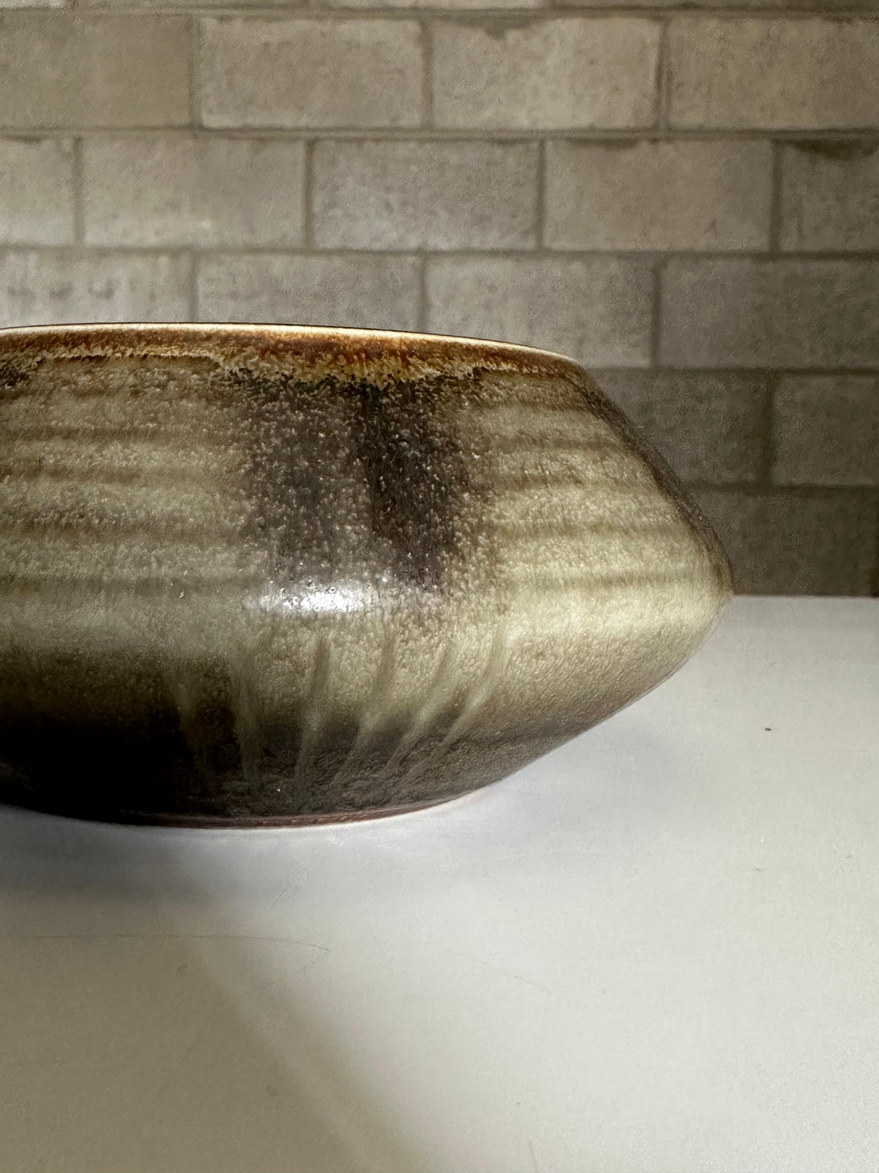 A ceramic bowl by Carl Harry Stålhane for Rörstrand. Features natural earth tones in green, tan, and light brown. Great beautiful and subtle decorative pattern. Well proportioned would allow for use as a decorative bowl or a low wide vase. 