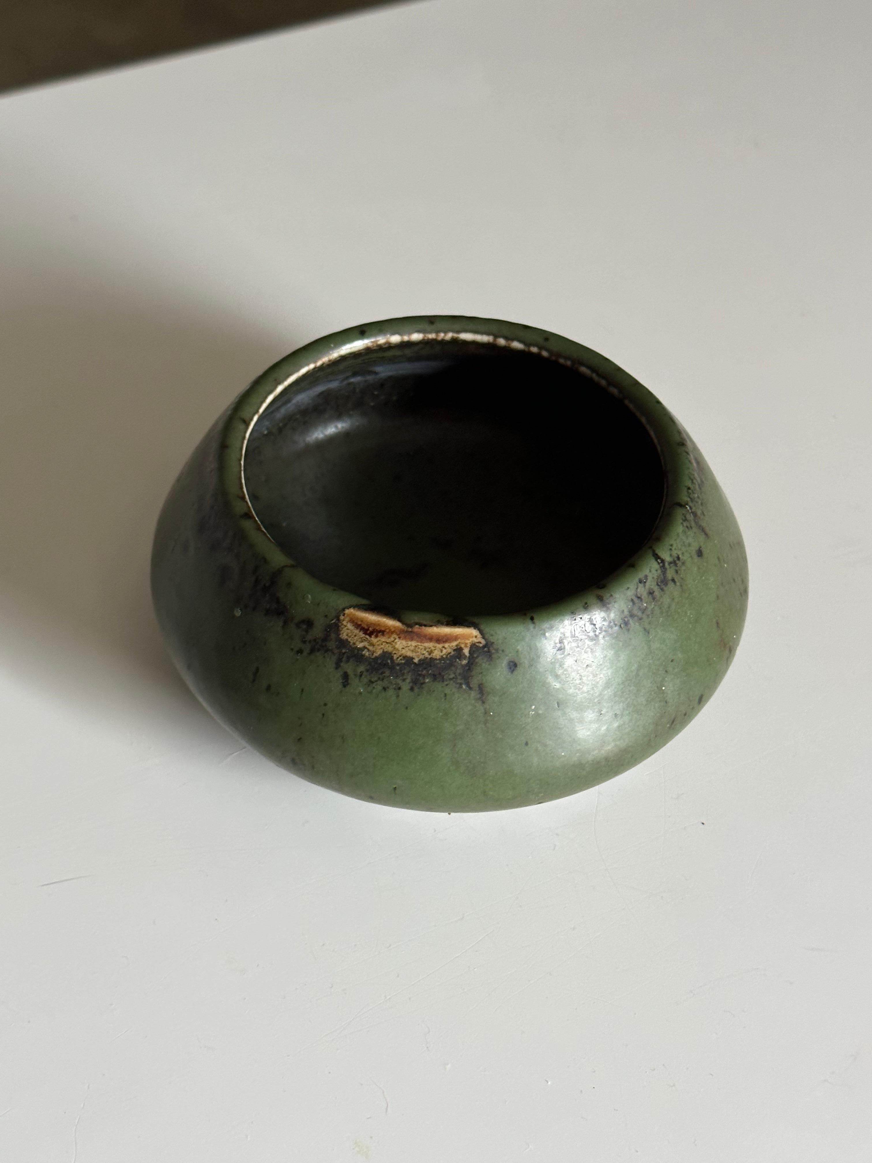 An unusual low vase or decorative bowl designed by Carl Harry Stålhane for Rörstrand. A wonderful predominately green glaze with areas of other colors showing through. A wonderful piece that would work in a variety of interiors.