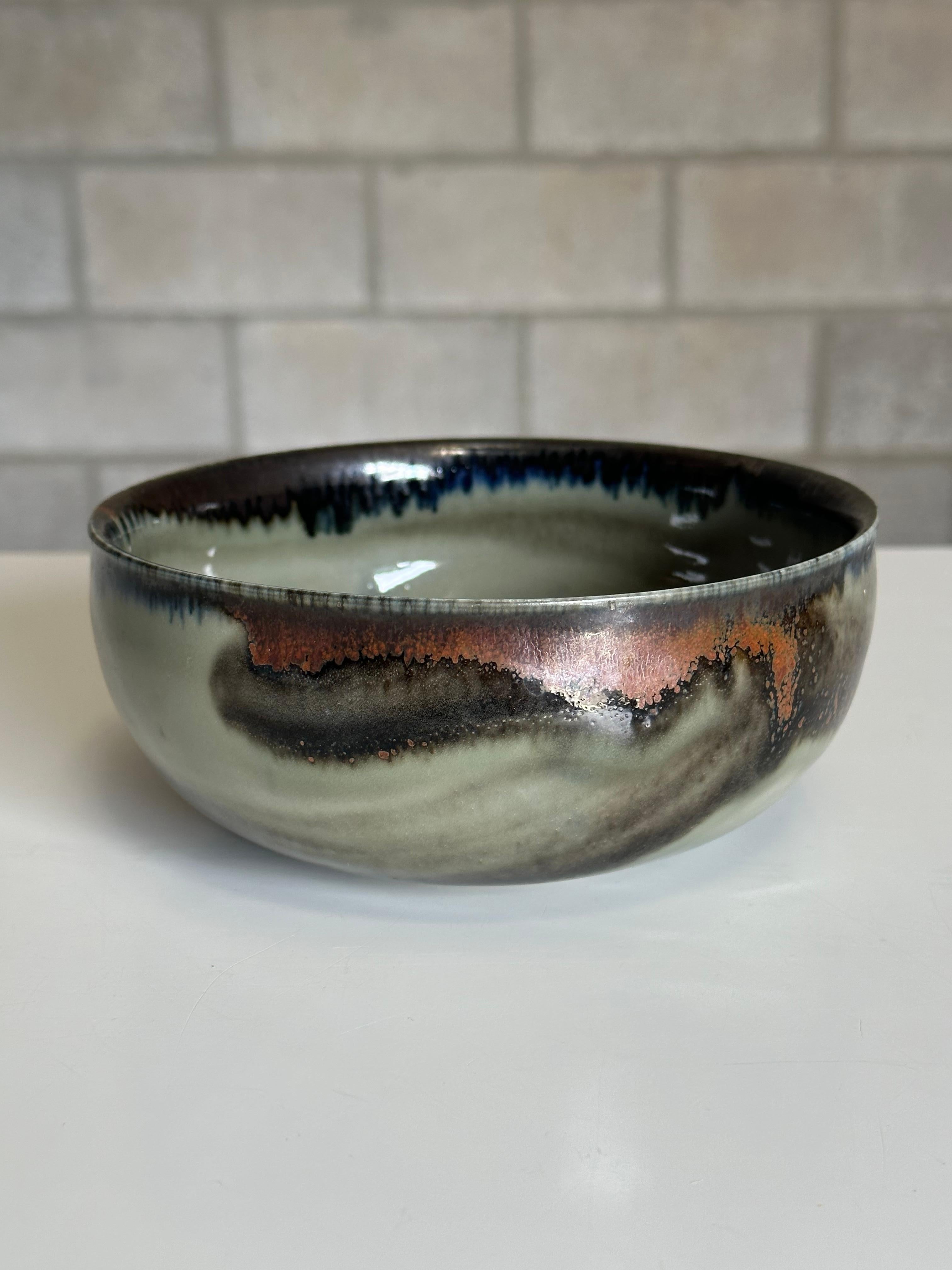 A unique bowl designed by Carl-Harry Stålhane for Rörstrand. Features an interesting green and black glaze with some areas having brown and gold tones present. Beautifully executed piece, and on the larger size vs most of his work
