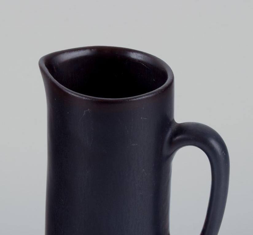Swedish Carl Harry Stålhane for Rörstrand. Ceramic jug with glaze in dark brown shades.  For Sale