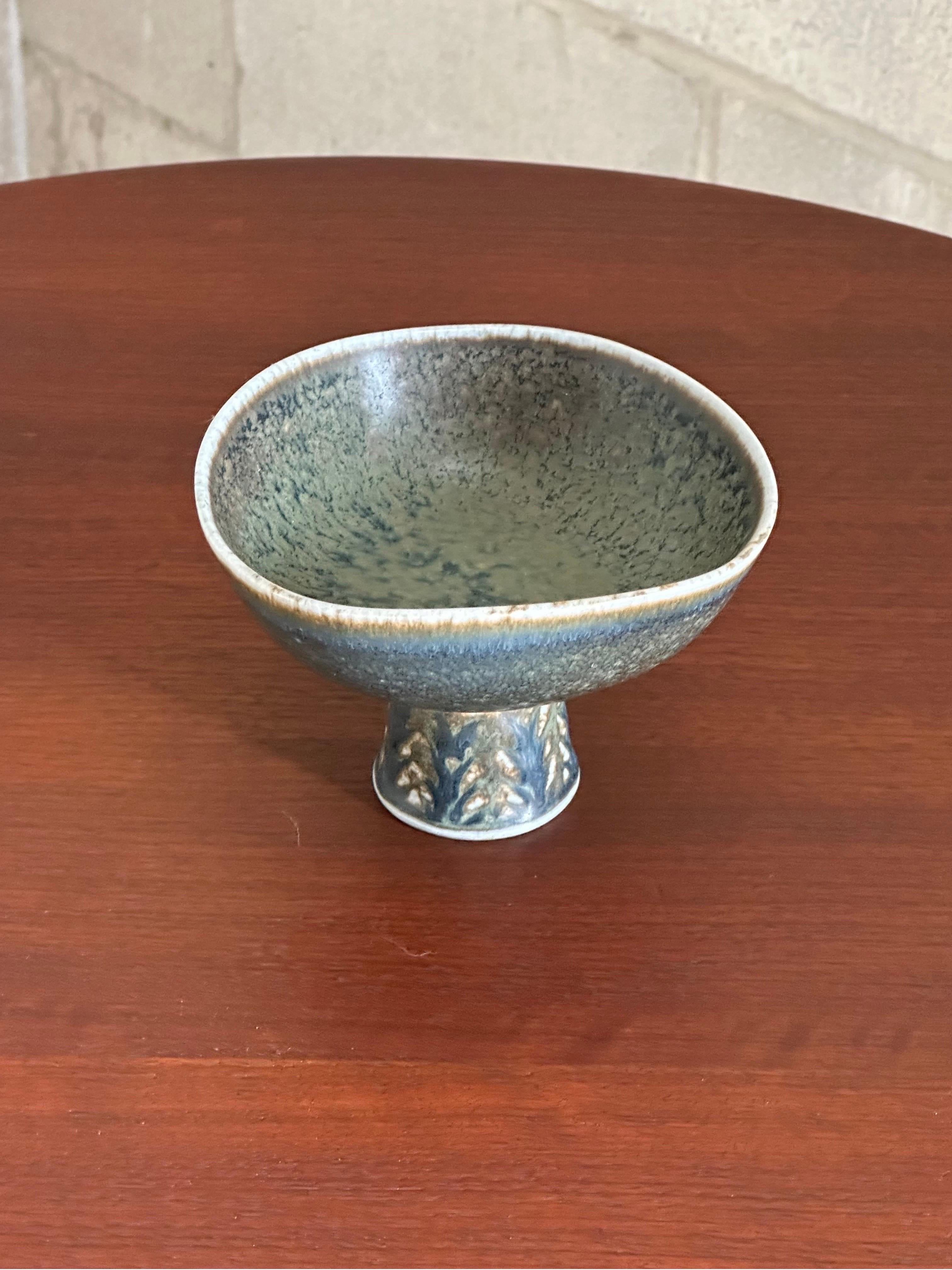 Wonderful footed bowl designed by Carl-Harry Stålhane for Rörstrand. Features a footed base with rounded freeform bowl. Lovely glaze and colors with blue, green, and brown.

Would work well in a variety of interiors including modern, mid century,