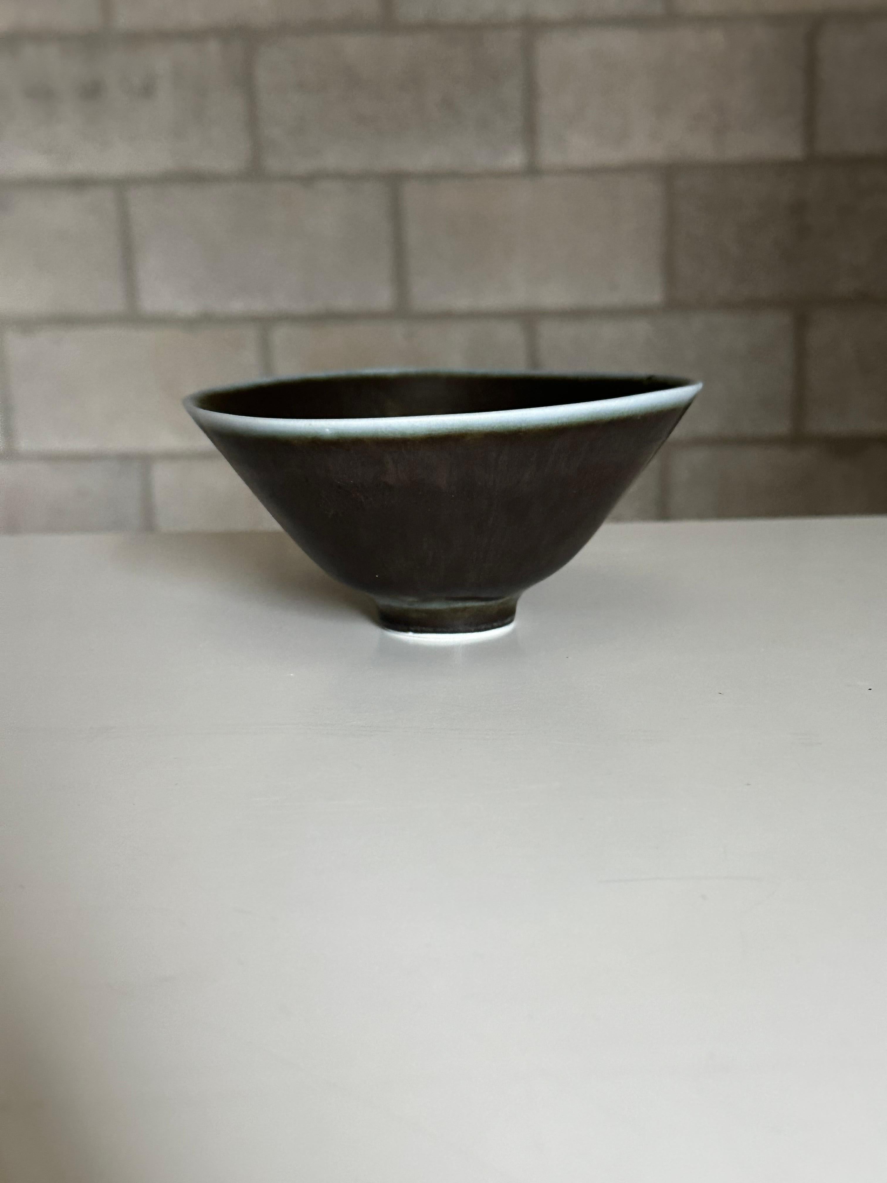 A charming bowl designed by Carl Harry Stålhane for Rörstrand. Bowl features a grayish blue body with an off white rim, some hues to brown. A very attractive color and shape- closer to the rim the bowl the shape begins to approach that of a rounded