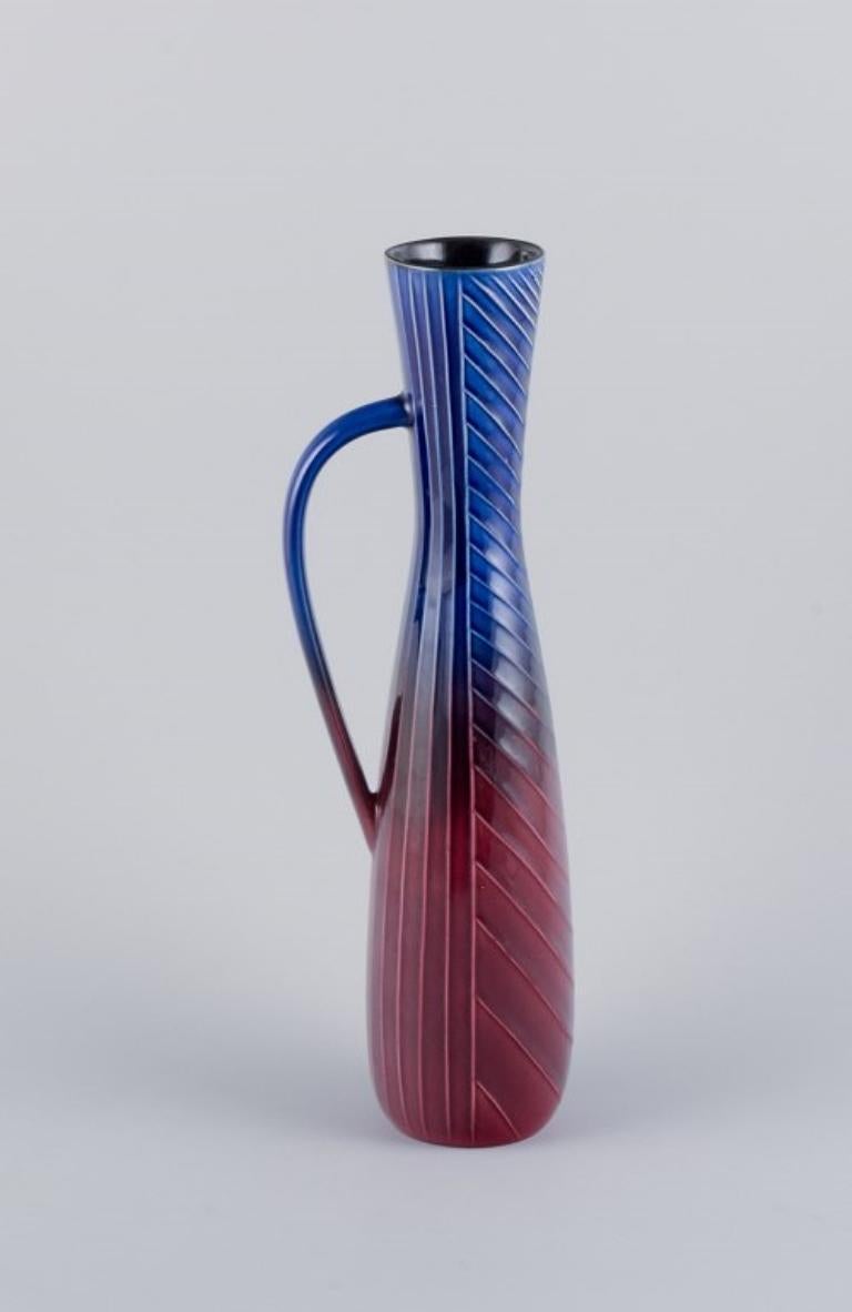 Carl Harry Stålhane for Rörstrand. Tall and slim ceramic pitcher in blue and burgundy tones.
Produced in the 1960s.
Stamped with the manufacturer's mark.
First factory quality.
In perfect condition.
Measures H 35.7 cm x D 10.0 cm (including handle).