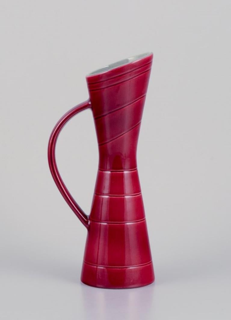 Carl Harry Stålhane (1920-1990) for Rörstrand. 
Two pitchers and a plate in ceramic. Burgundy-colored glaze.
From the 