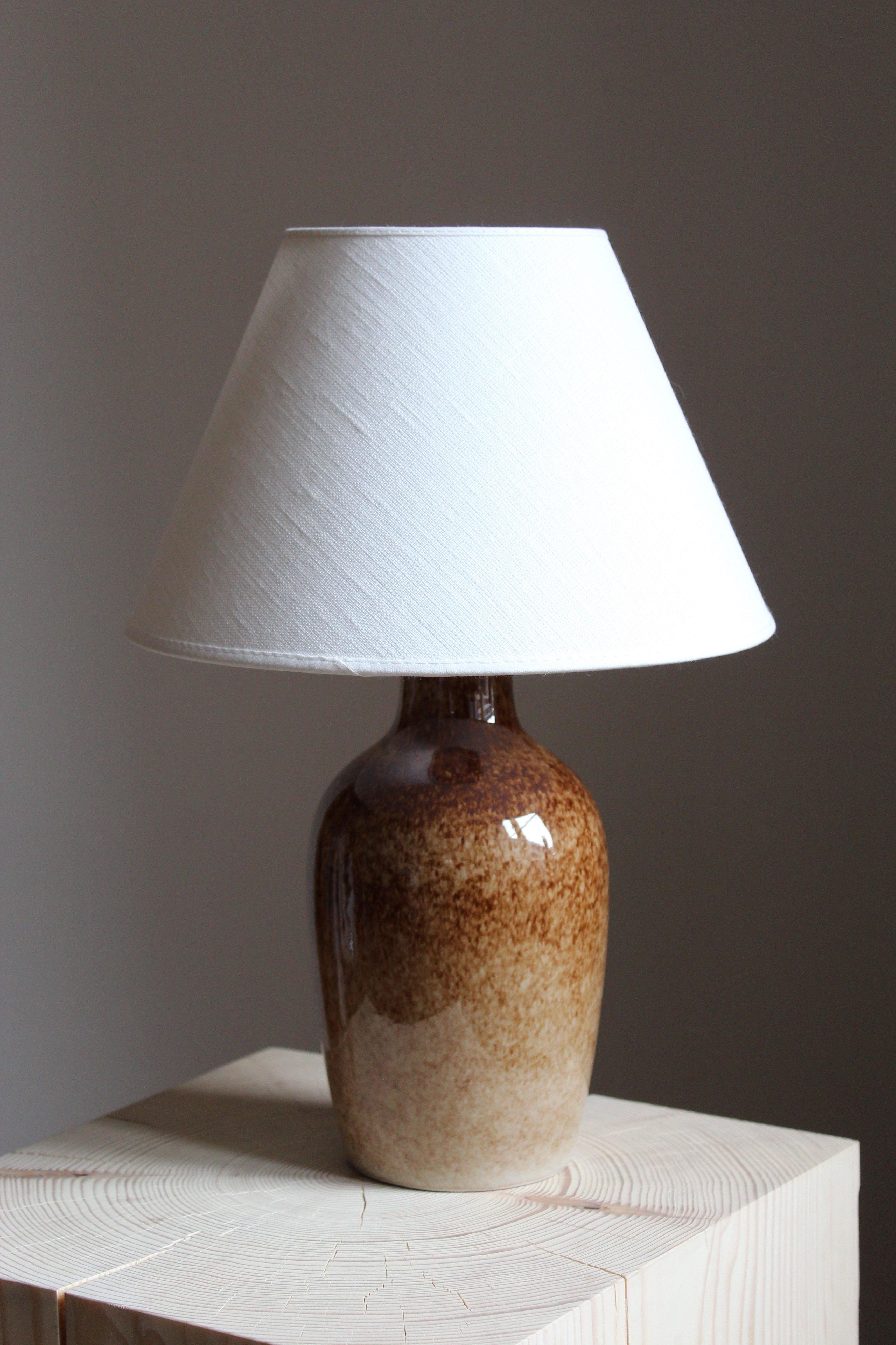 A table lamp by Carl-Harry Stålhane and potter Kent Eriksson, for Carl-Harry Stålhanes own studio, Designhuset, Sweden. Signed. Sold without lampshade.

Glaze features brown-beige colors.

Other ceramicists of the period include Berndt Friberg, Axel