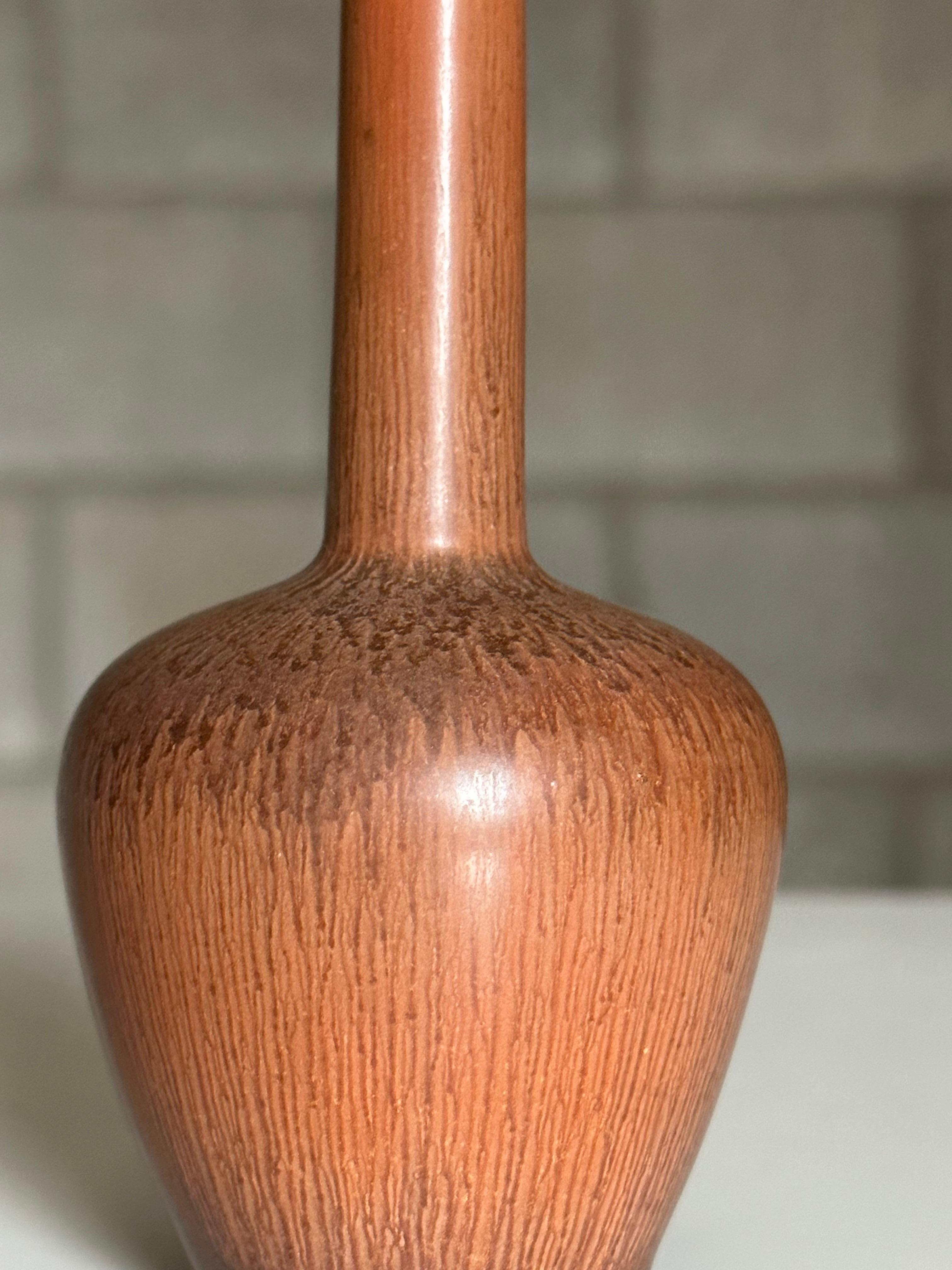 Magnifique petit vase conçu par Carl-Harry Stålhane pour Rörstrand. Il se caractérise par un corps bulbeux et un cou fin et long. Le vase est complété par une superbe couleur terre cuite.