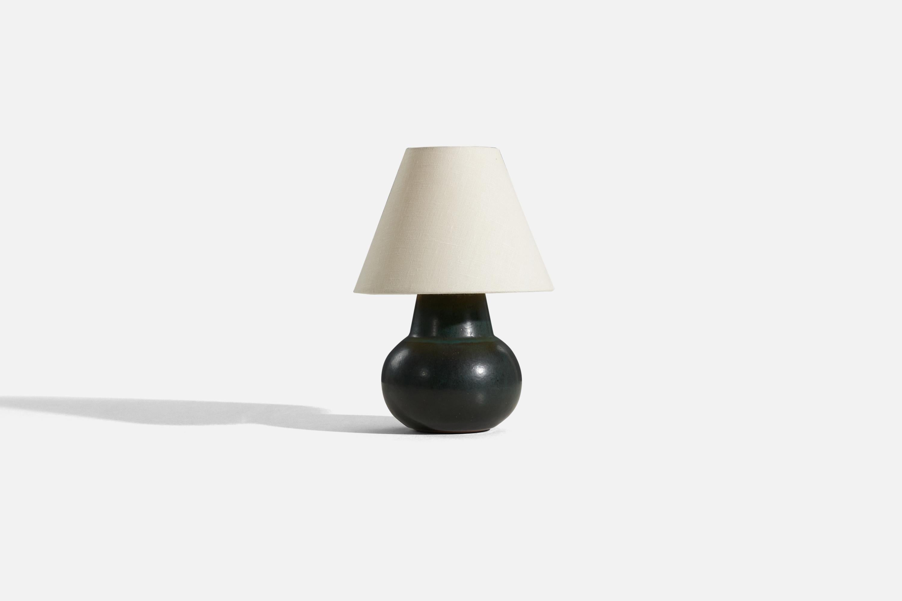 A dark green-glazed stoneware table lamp designed by Carl-Harry Stålhane and produced by Rörstrand, Sweden, c. 1960s. 

Sold without lampshade. 
Dimensions of Lamp (inches) : 7 x 5.375 x 5.375 (H x W x D)
Dimensions of Shade (inches) : 4 x 8.25