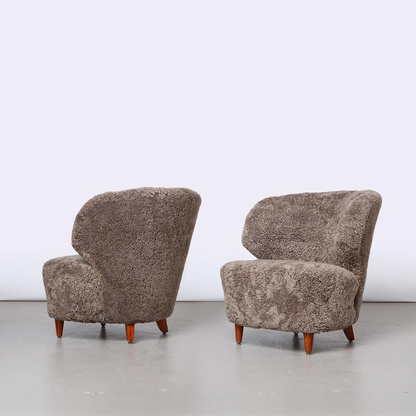 Pair of Finnish curved easy chairs, designed by Carl-Johan Boman. Produced by Oy Boman Ab in Finland, 1940s. Tapered wooden legs, seats are newly upholstered in Sahara sheepskin.

Please note that these easy chairs are also sold individually. Please