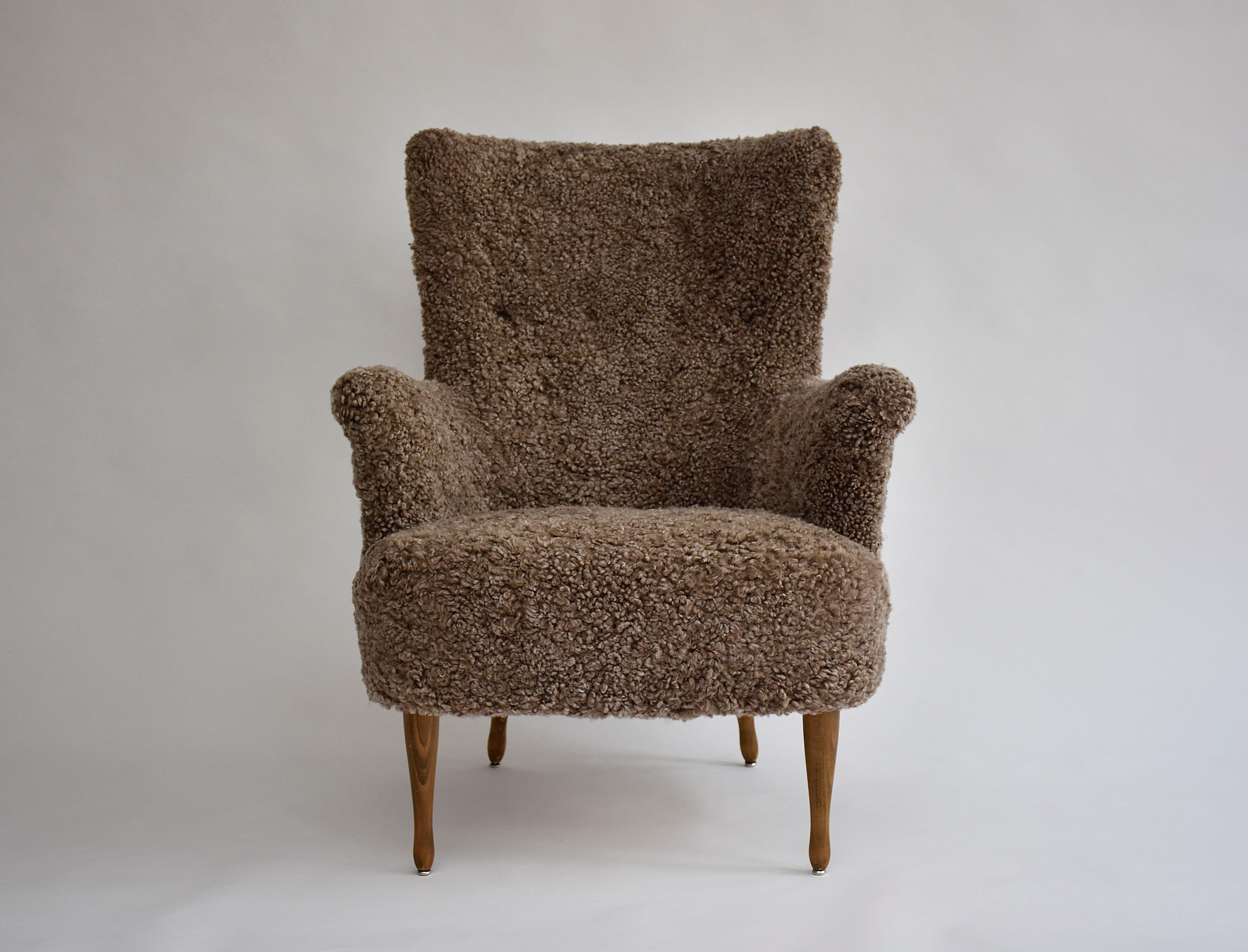 A stunning armchair by the famous furniture designer- Carl Malmsten.
This iconic chair provides great comfort and is of enduring quality. 
Back tufted by buttons, elegant arm curves and wooden legs. 
New soft upholstery in grey/brown