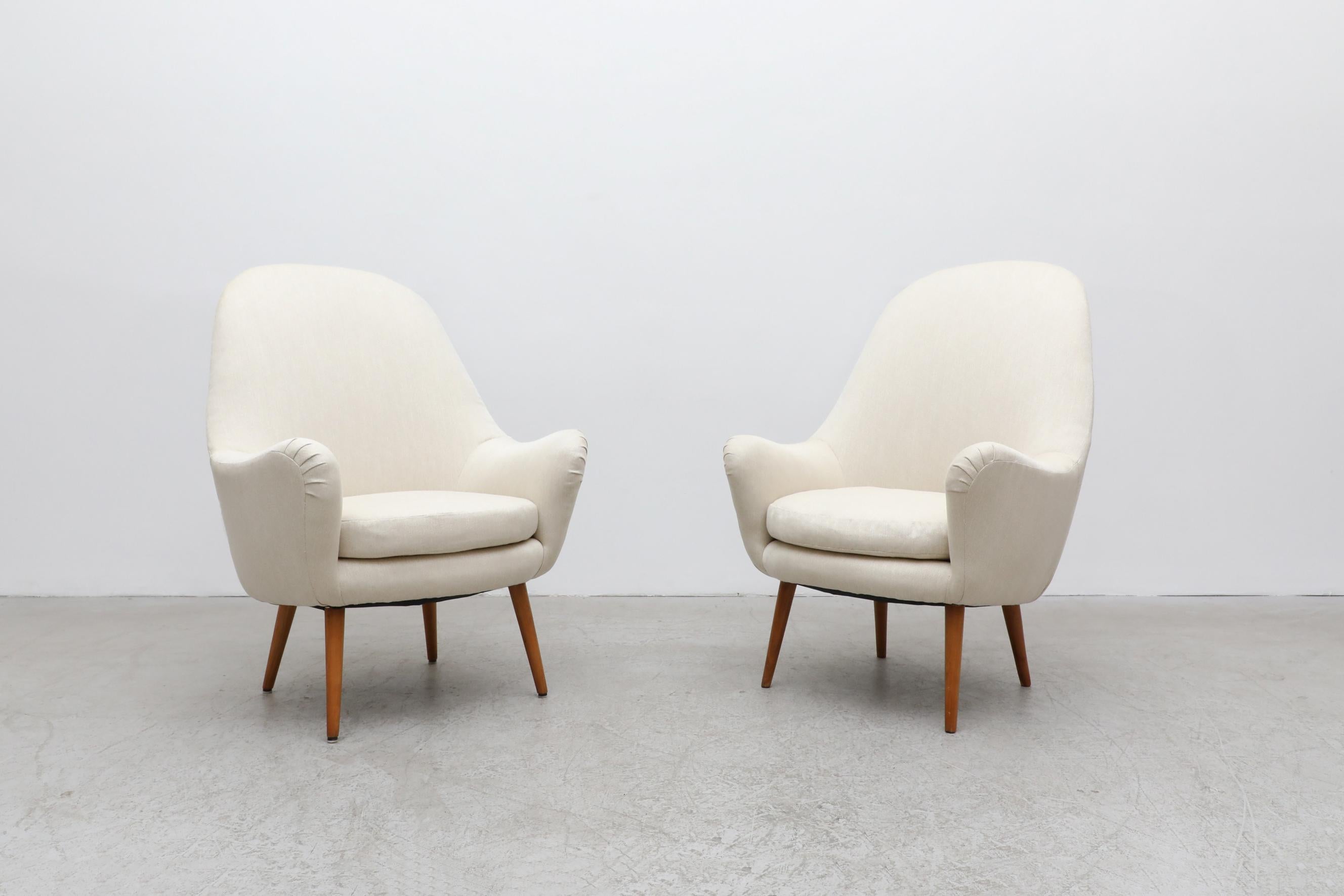Dramatic, Mid-Century, Swedish, upholstered lounge chairs attributed to post-war design luminary Carl Malmsten with handsomely tapered legs and a new ivory upholstery. Carl Malmsten was a Swedish furniture designer, architect, and educator who was