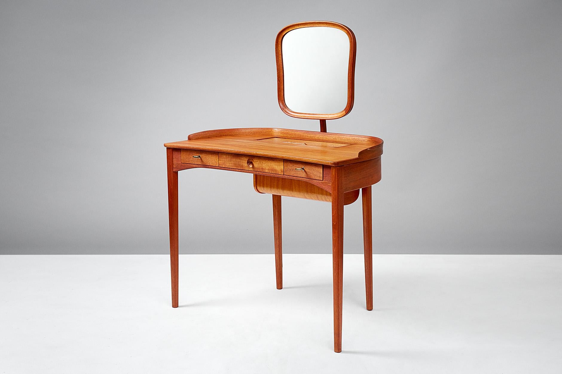 Carl Malmsten

Birgitta dressing table, 1964

Exquisite dressing table produced by Bodafors, Sweden in light mahogany. Adjustable mirror with brass fittings, 3 front drawers with original keys. Additional storage in desk top with tambour door.