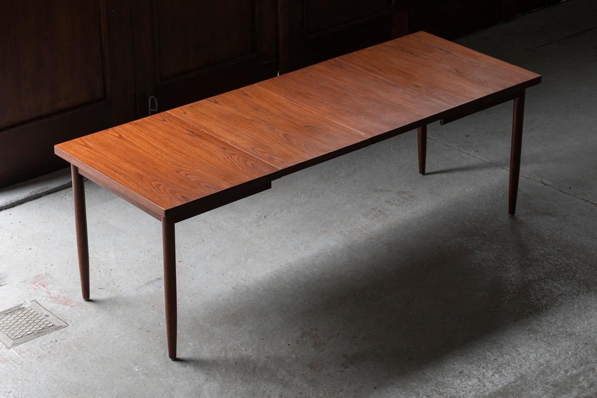 Extendable teak dining table designed  and produced n the 1960s. This rectangular table is made out of quality teak veneer combined with a solid frame and solid teak legs. The round surface can be extended 2 extra leaves of 50 cm each to a maximum