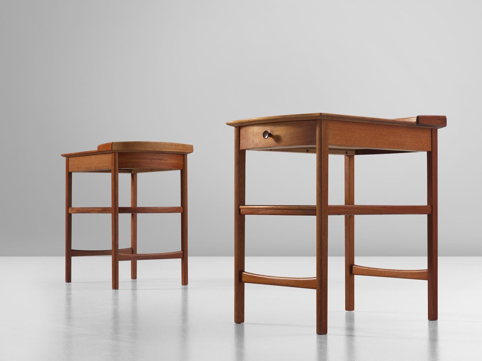 Carl Malmsten for Bodafors, pair of side tables, mahogany, Sweden, 1962.

This modest set of nightstands is designed by the Swede Carl Malmsten. The table feature an underlying shelf and rail with small drawer. The drawers are finished with a