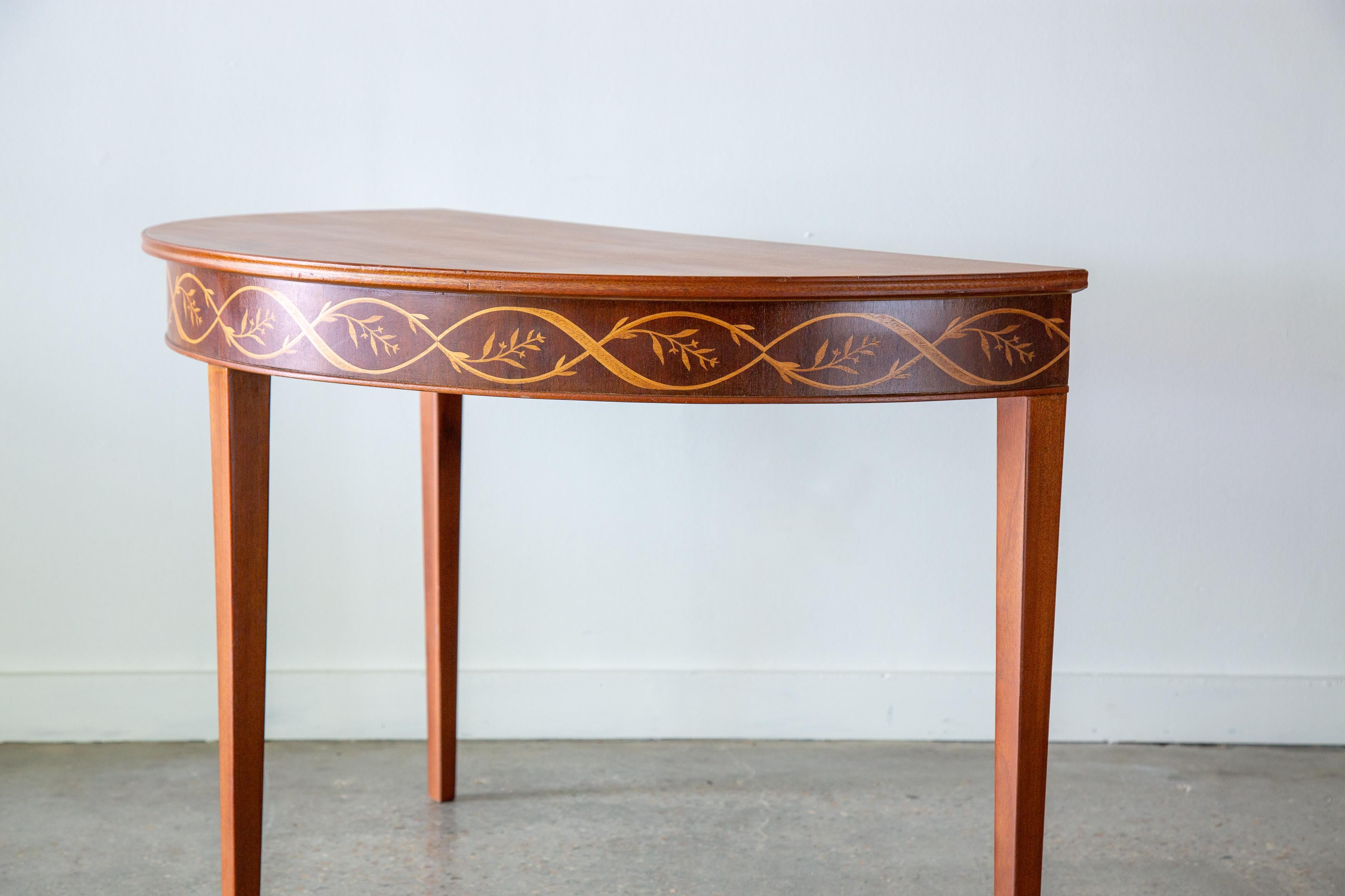 A mahogany demilune table designed by Carl malmsten. Circa 1950s Sweden. Intricate interlaced birch and rosewood veneers sweep the outer edges of the table. Contrasting and complimenting wood species provide great visual affect. Priced per table.
